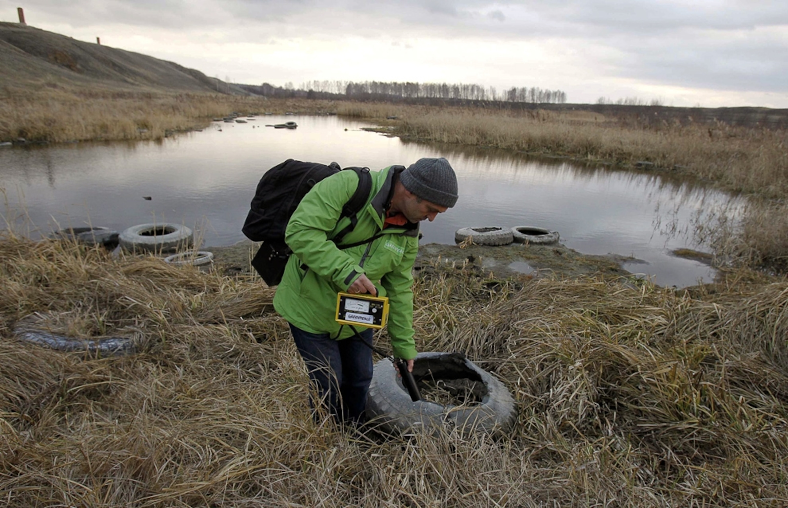 A man walks a riverbank measuring levels of radioactive waste.