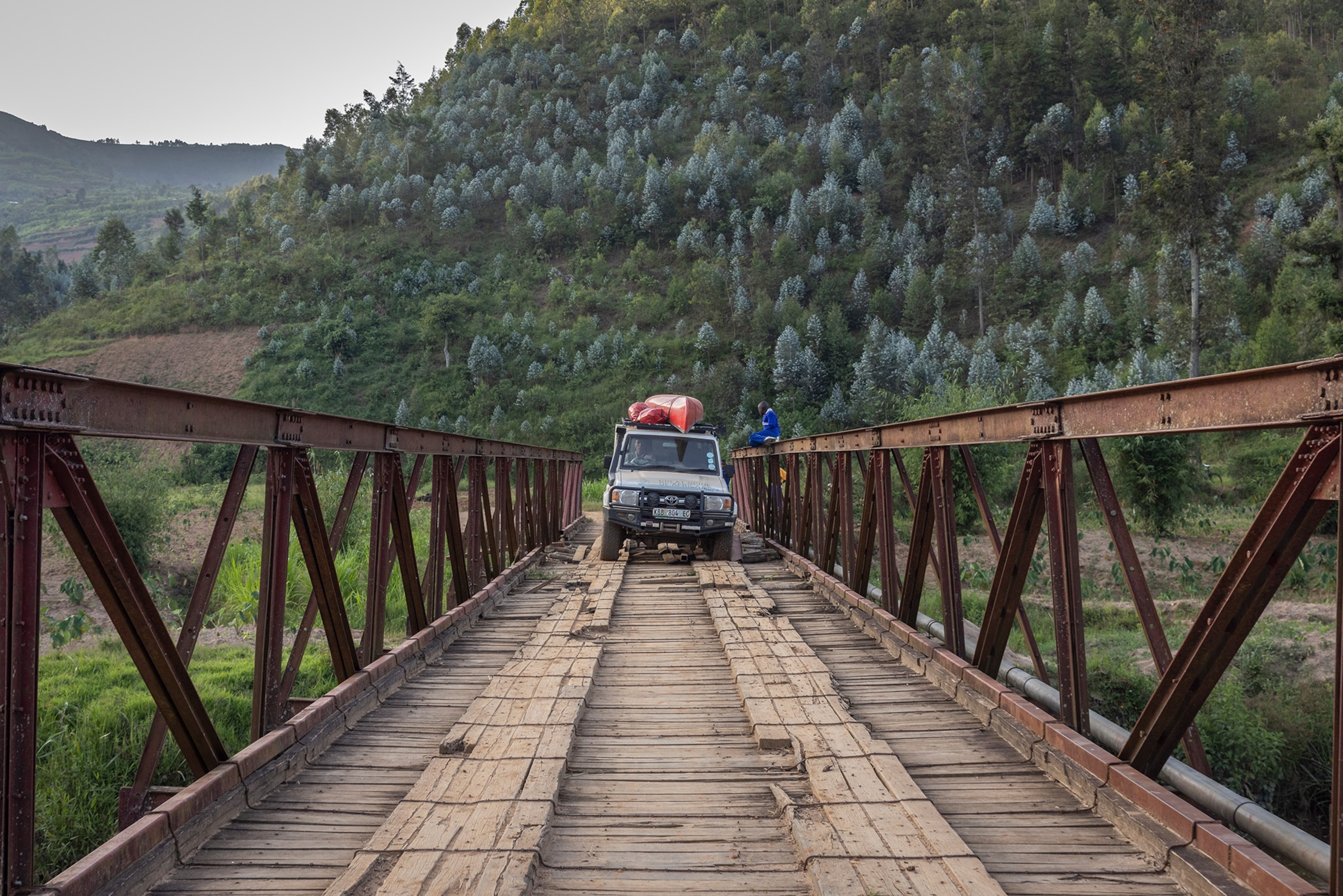 expedition car loaded with canoes crossing a bridge