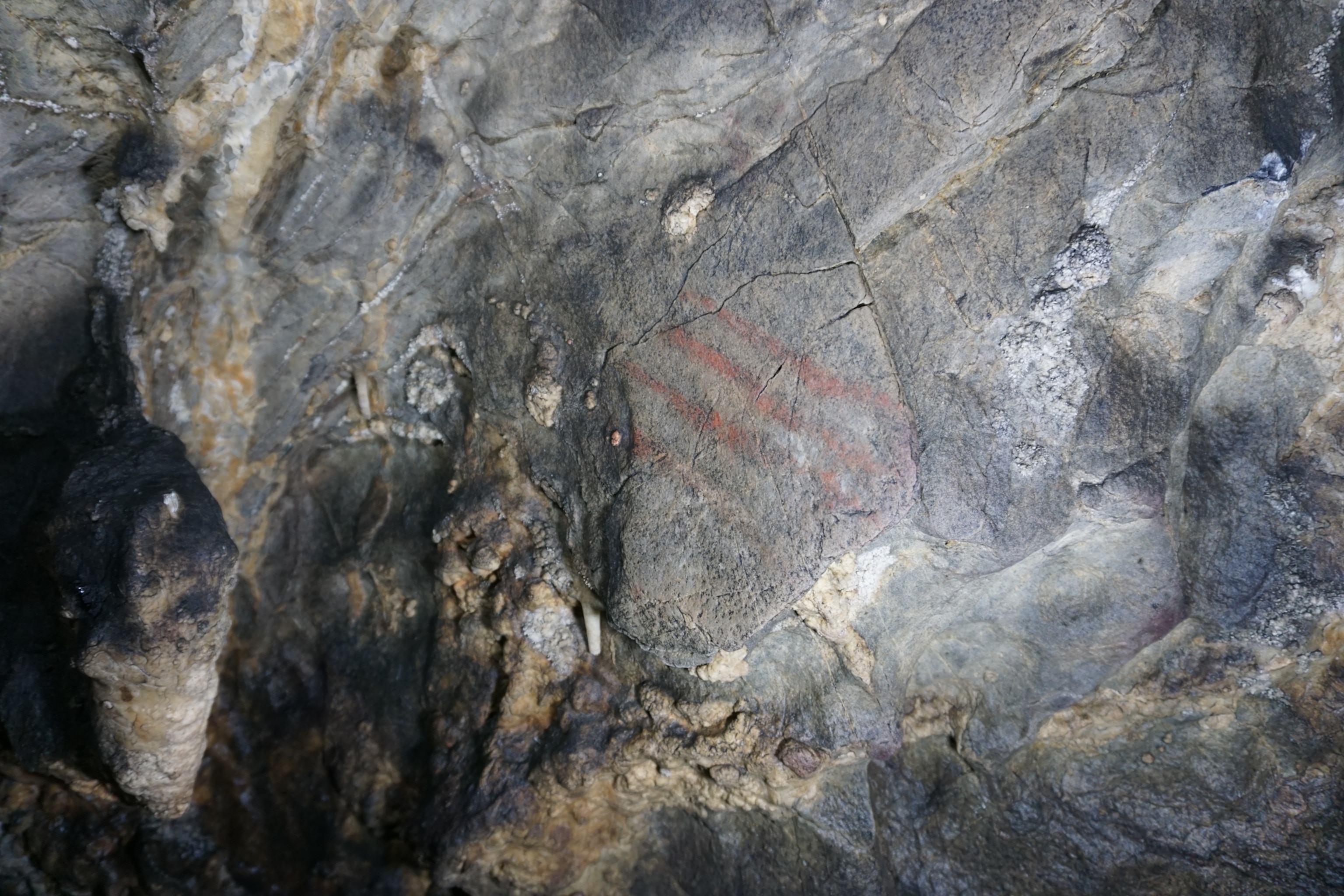 Close-up of a textured rock surface with faint red stripes painted diagonally