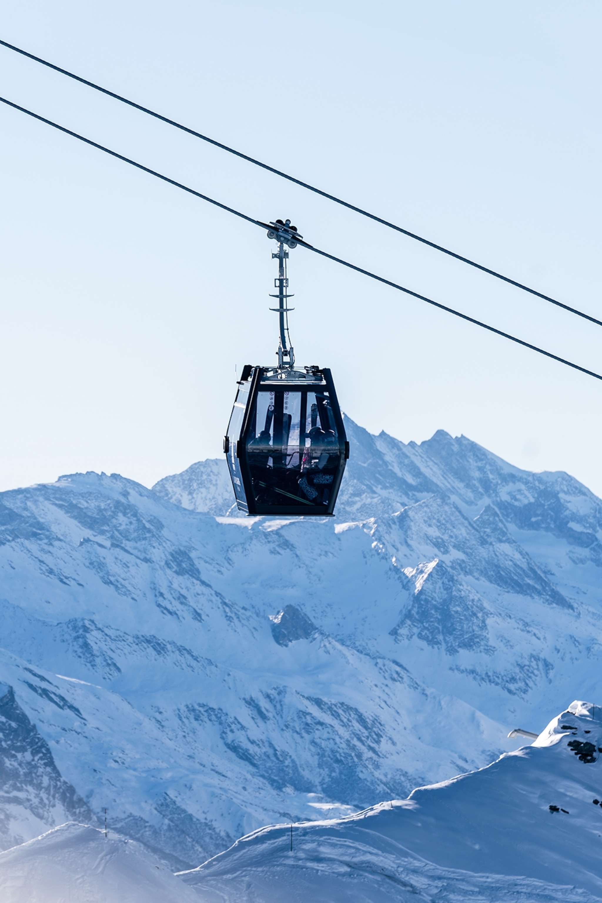 A gondola suspended in the air with a snowy landscape below.