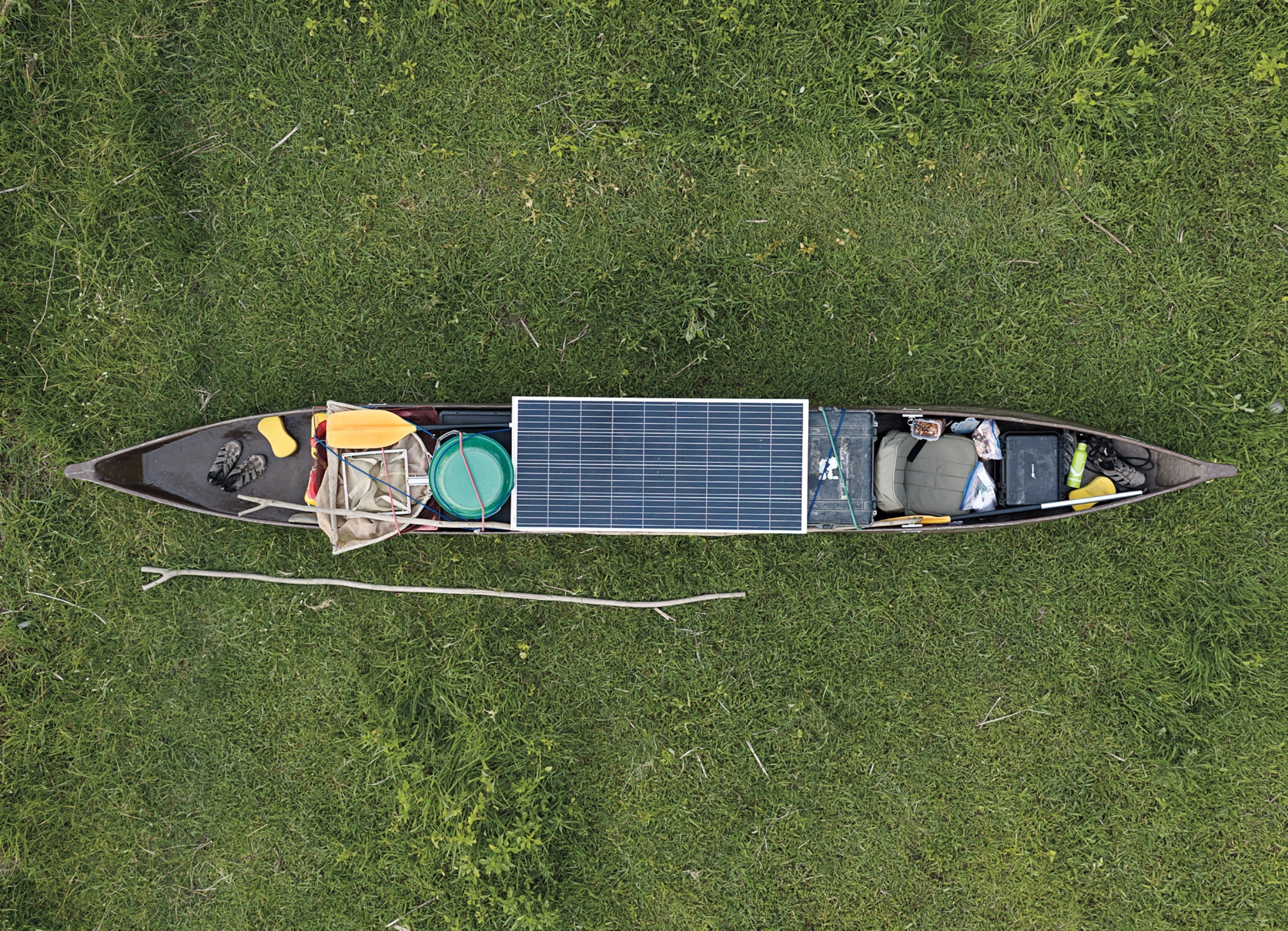 View from above at research and expedition gear with solar panel on top packed into canoe.