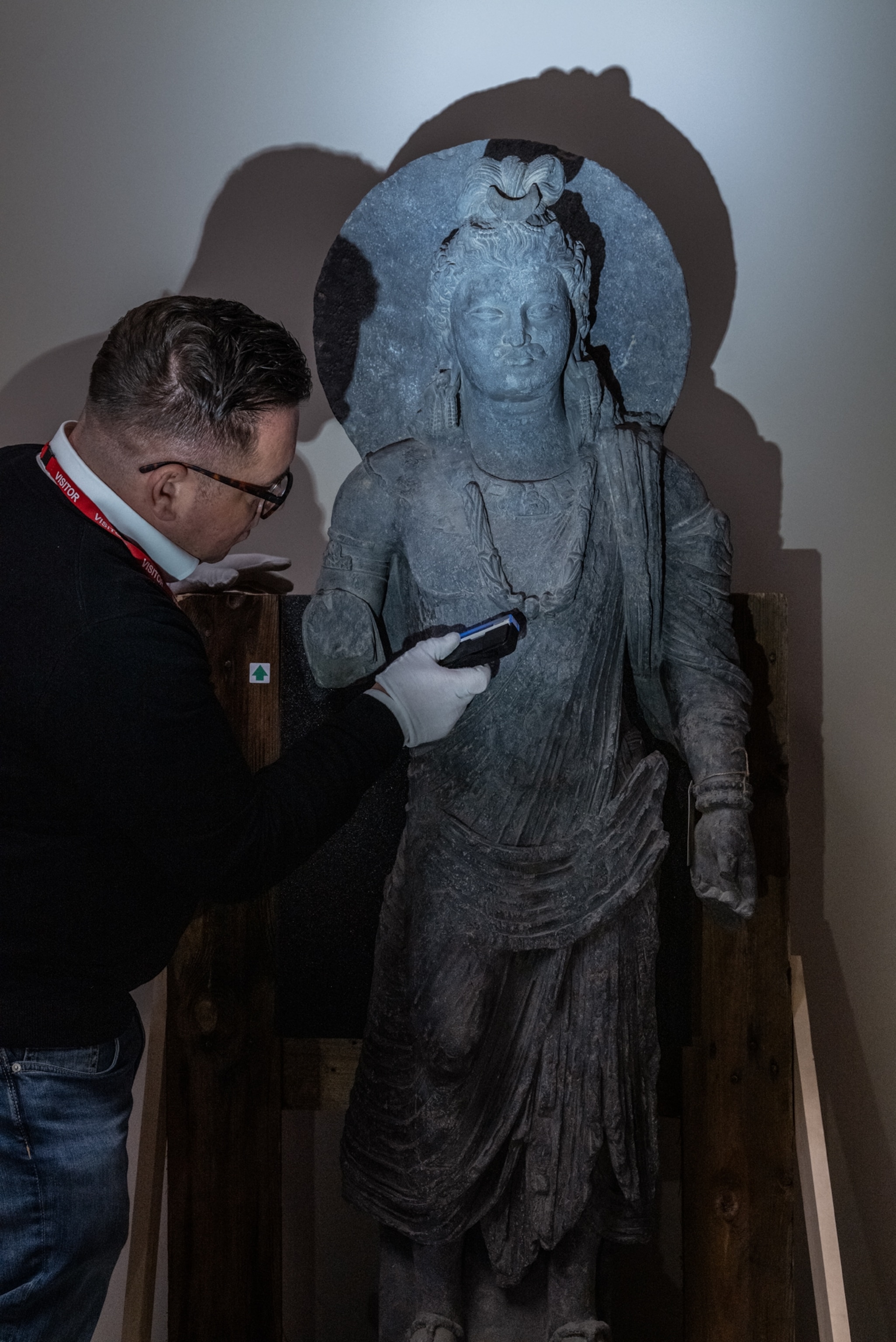A researcher looks at a tall statue holding a black light