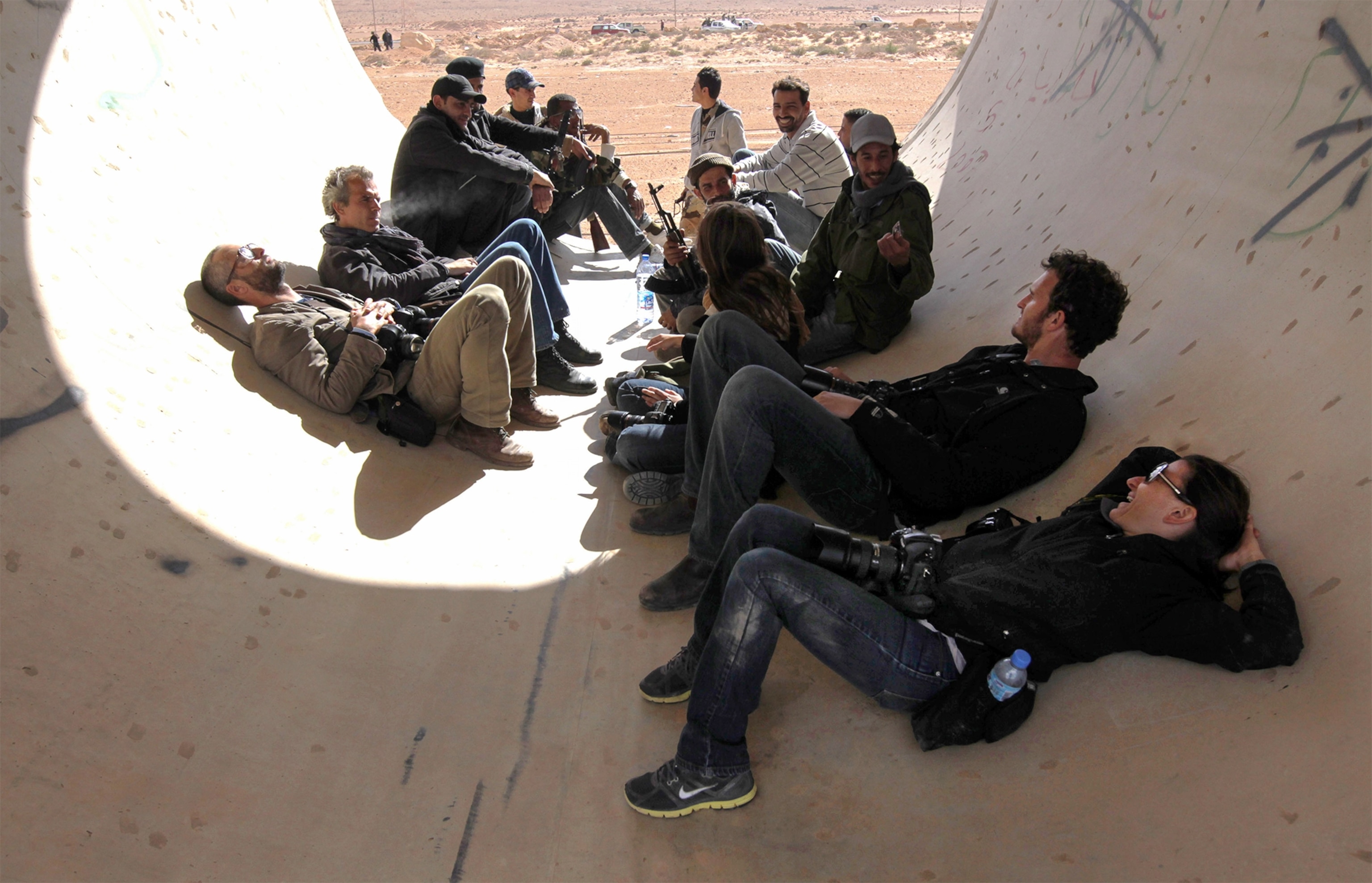 photojournalists resting in a construction pipe during fighting in Libya