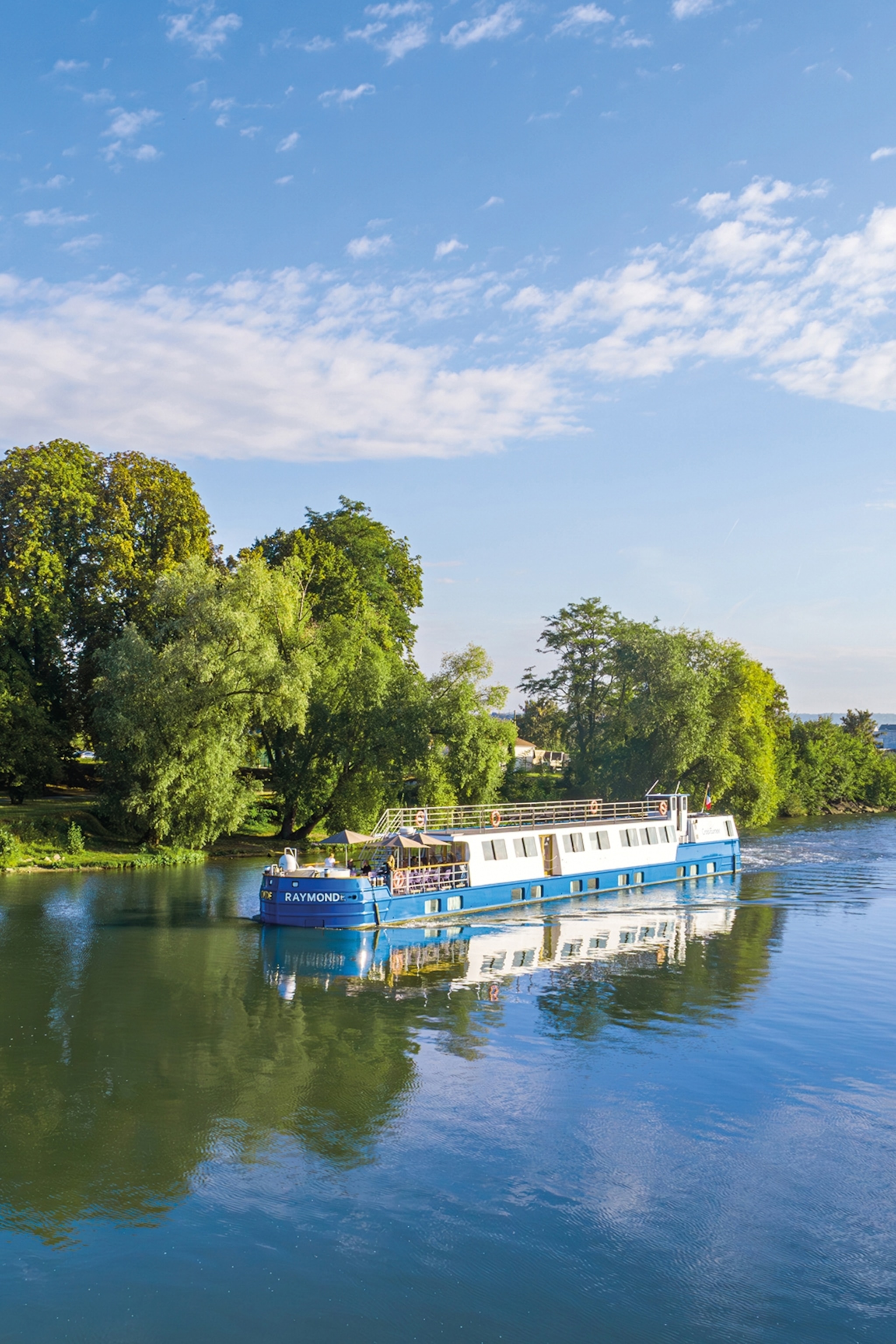 A canal cruise boat going down a quiet waterway.