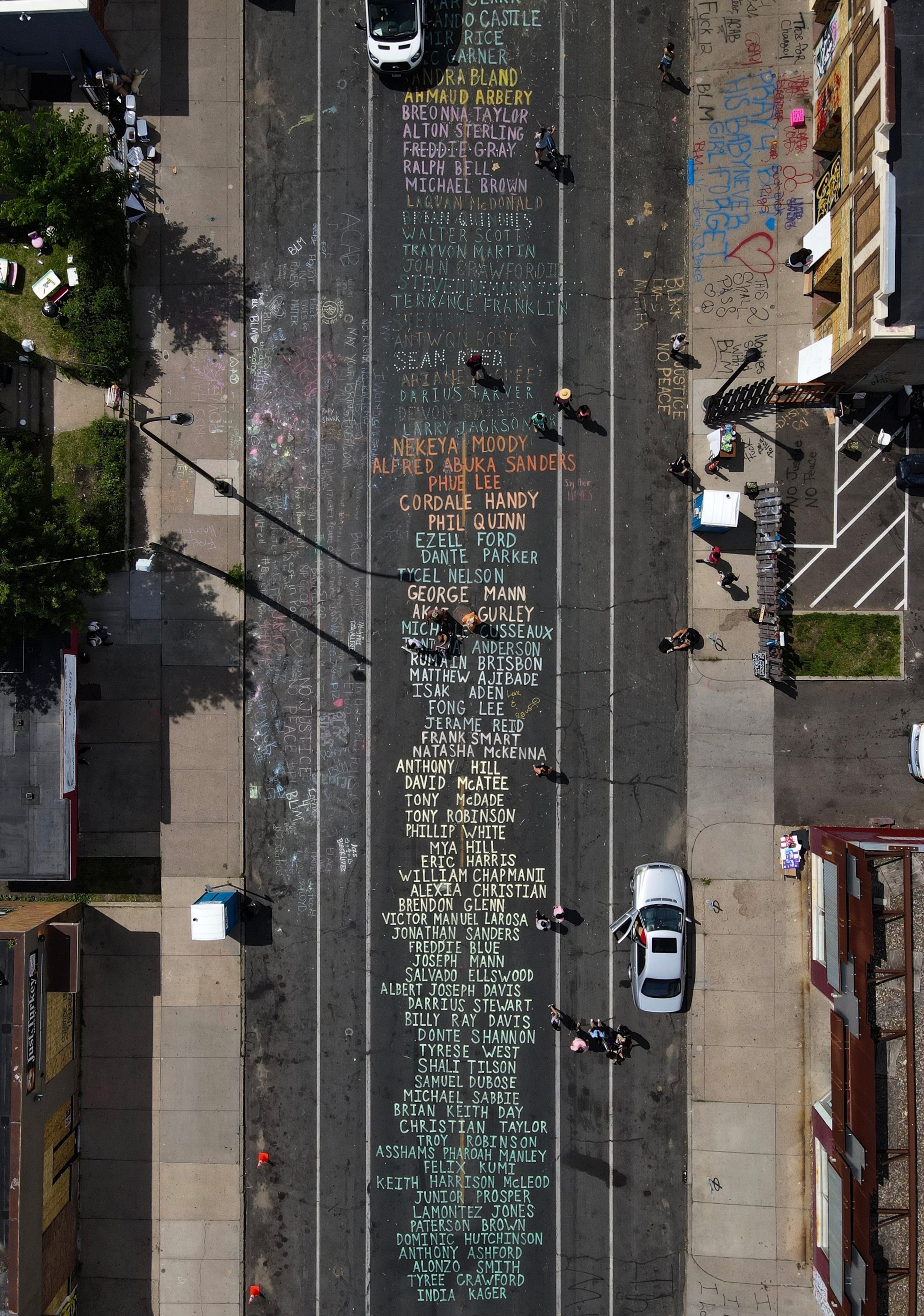 a street from above with names of those killed by police written on the pavement