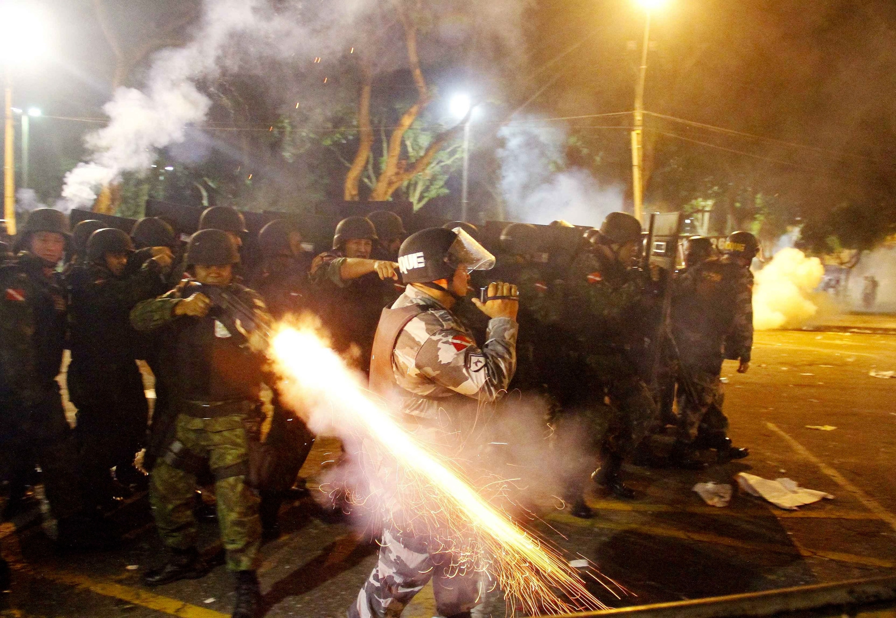 A riot policeman fires a weapon while confronting demonstrators in Belem, Brazil.