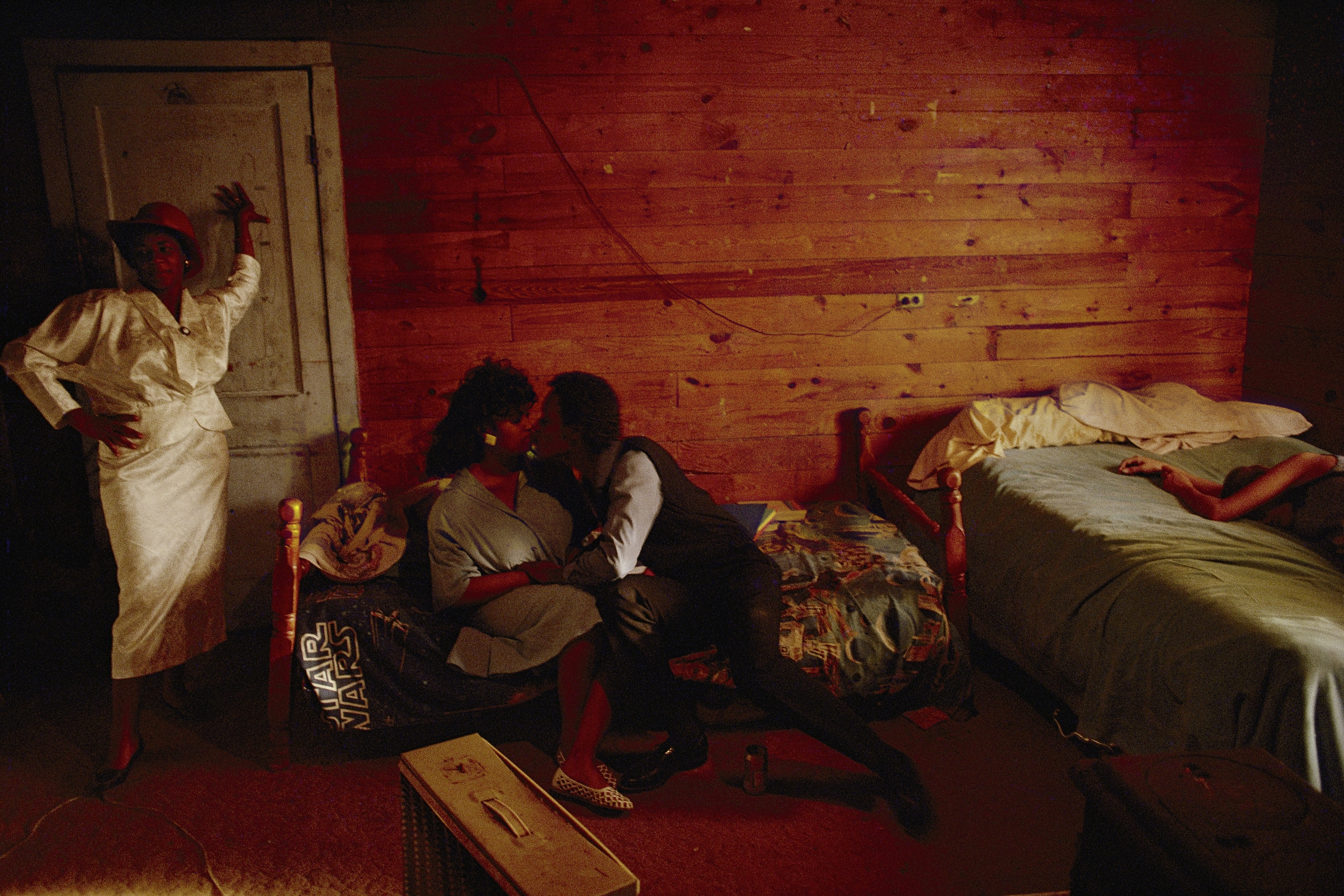 A man busses a woman while friends relax at a bluesman's home.