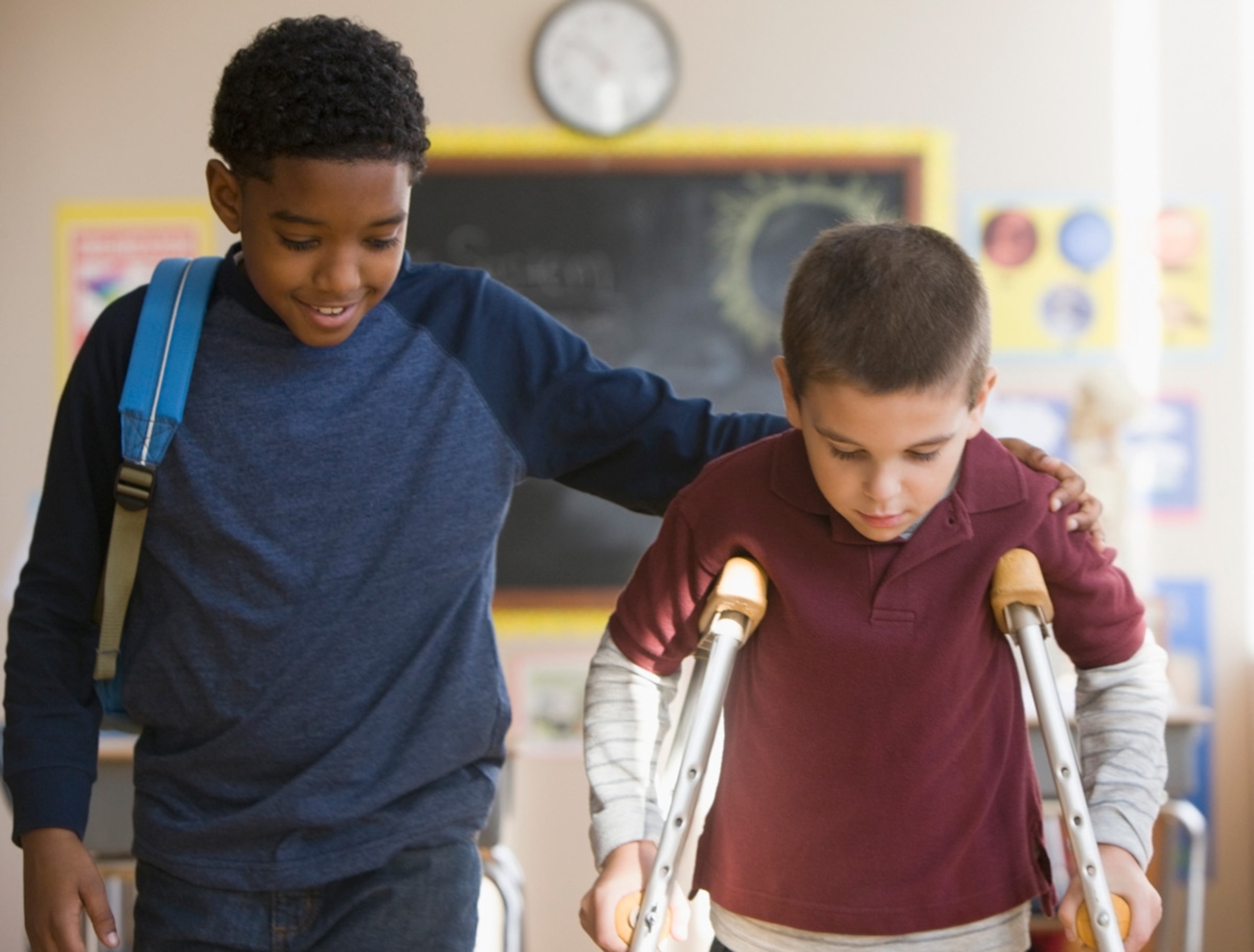 Boy walking with friend on crutches, New York.