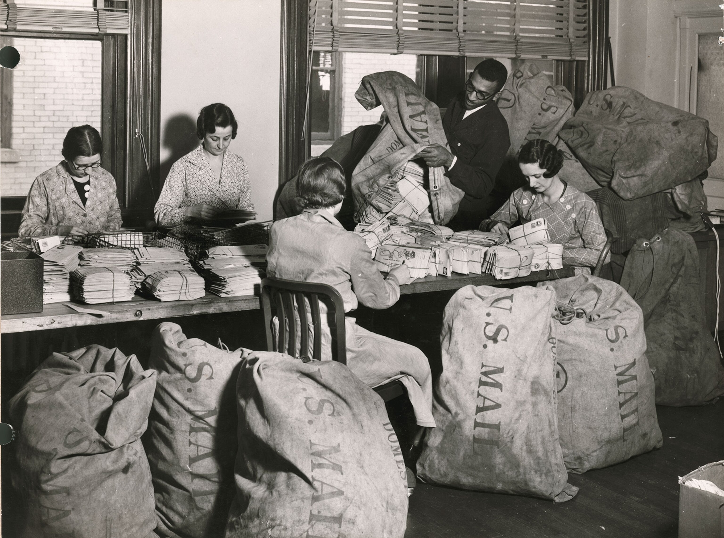 men and women sorting mail.