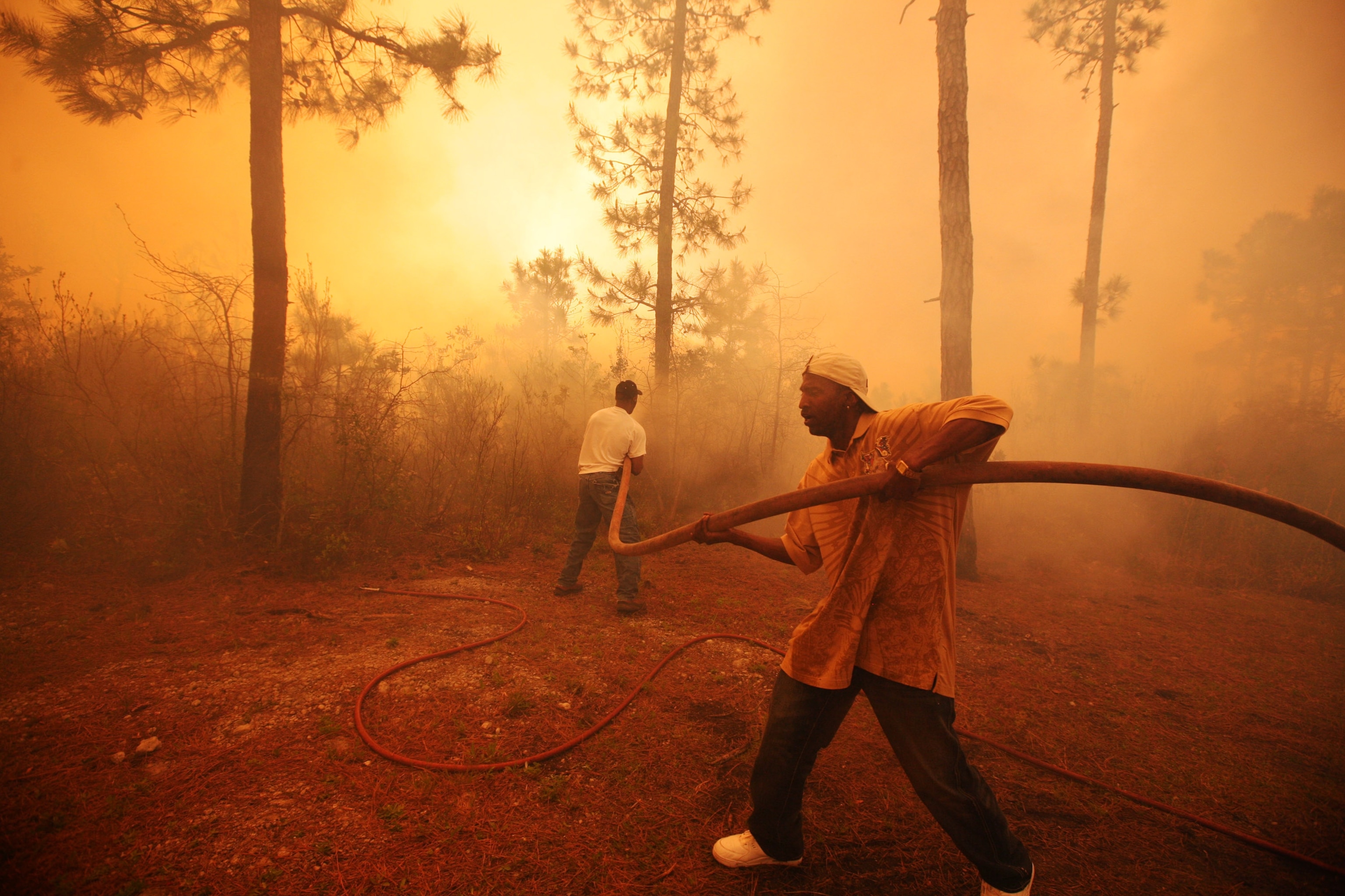 two men use a hose to spray water on a fire