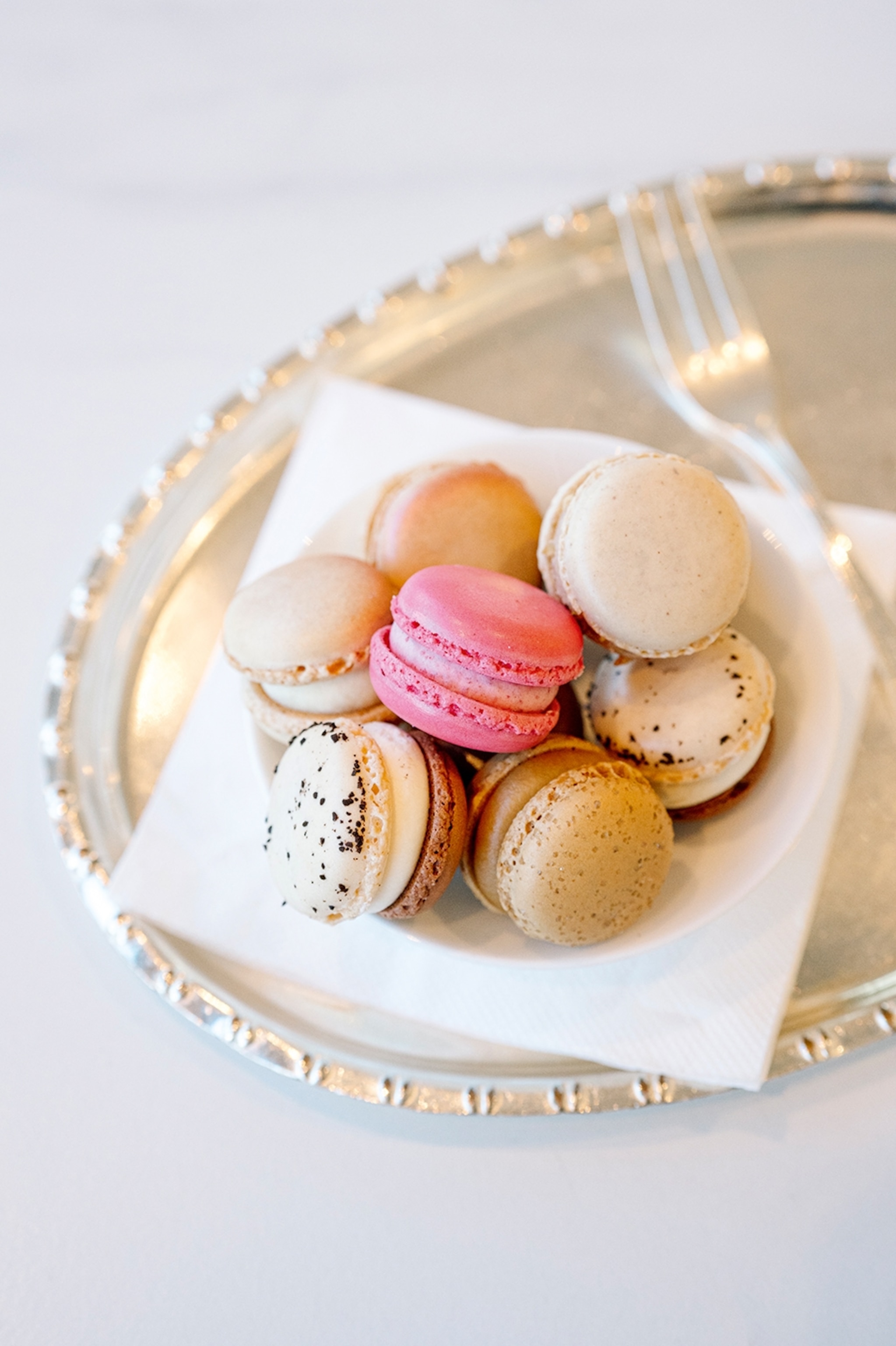 A close-up of a silver plate with multiple macarons.