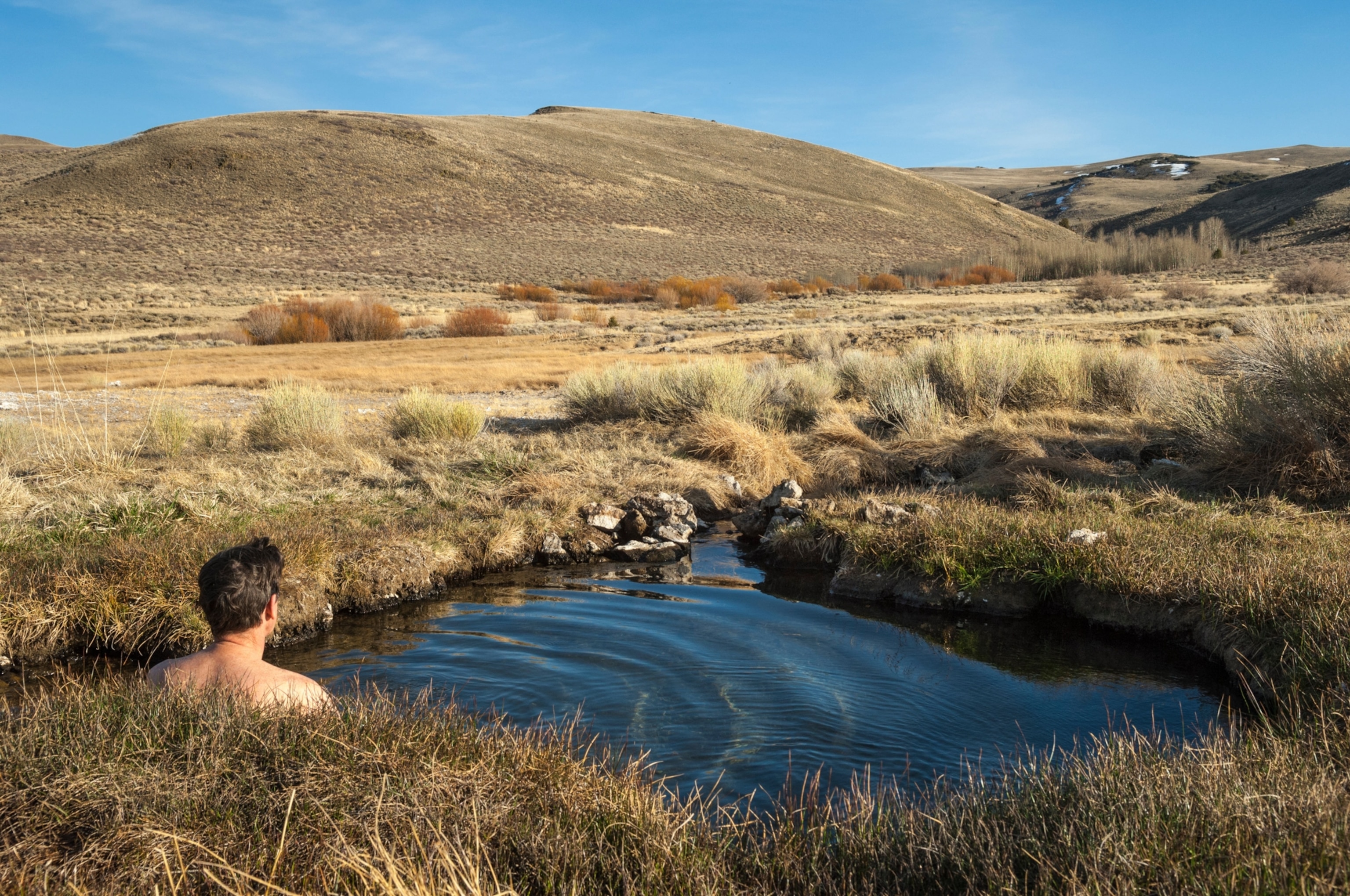 A man in a pool of water looking out at the landscape.
