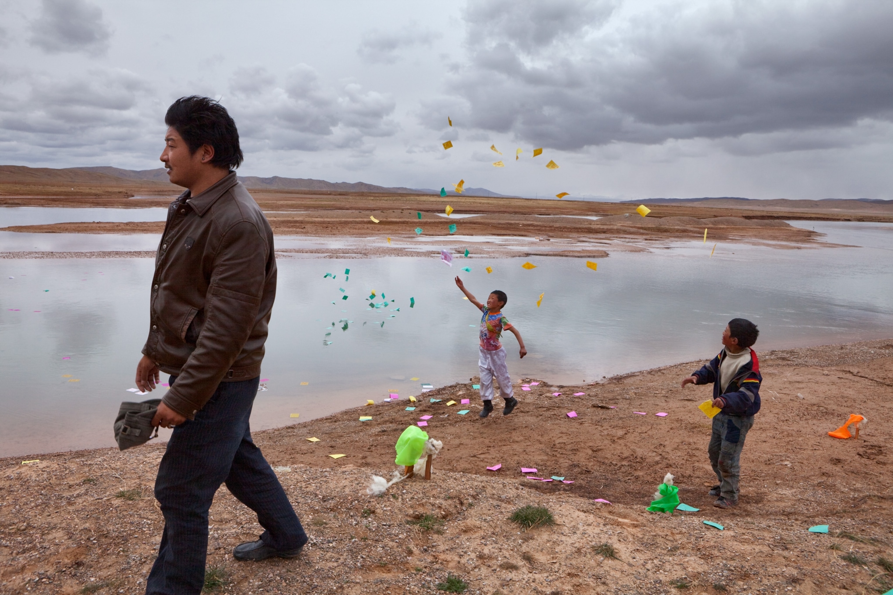 a Tibetan boy flinging prayer cards into the Yellow River