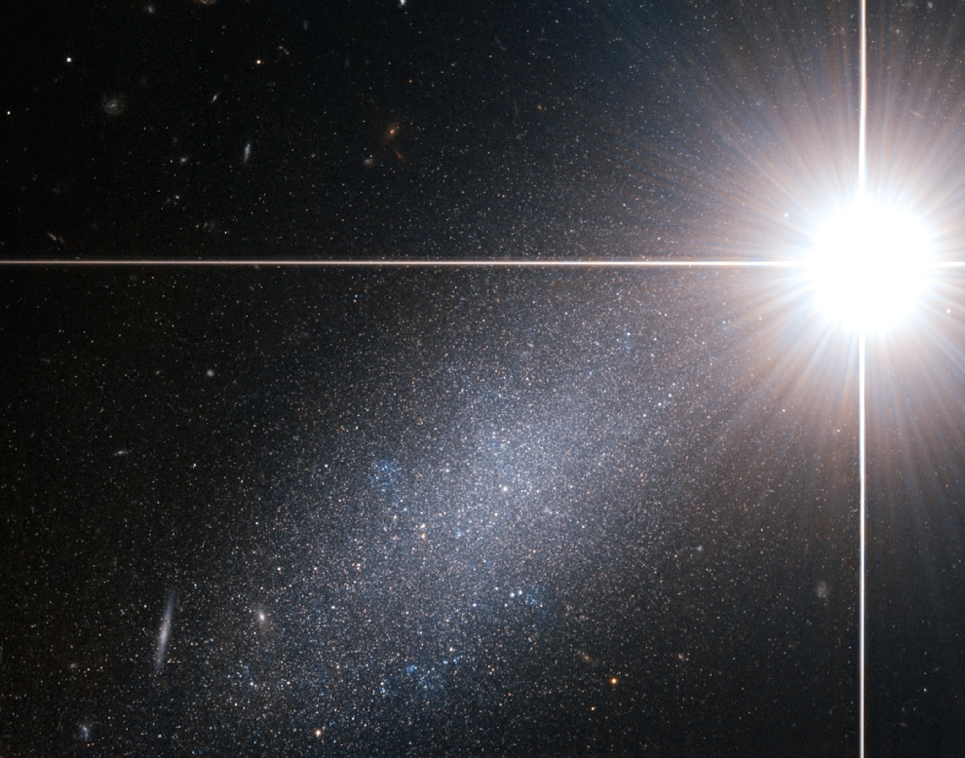 Picture of a dwarf galaxy almost obscured by light from a foreground star.