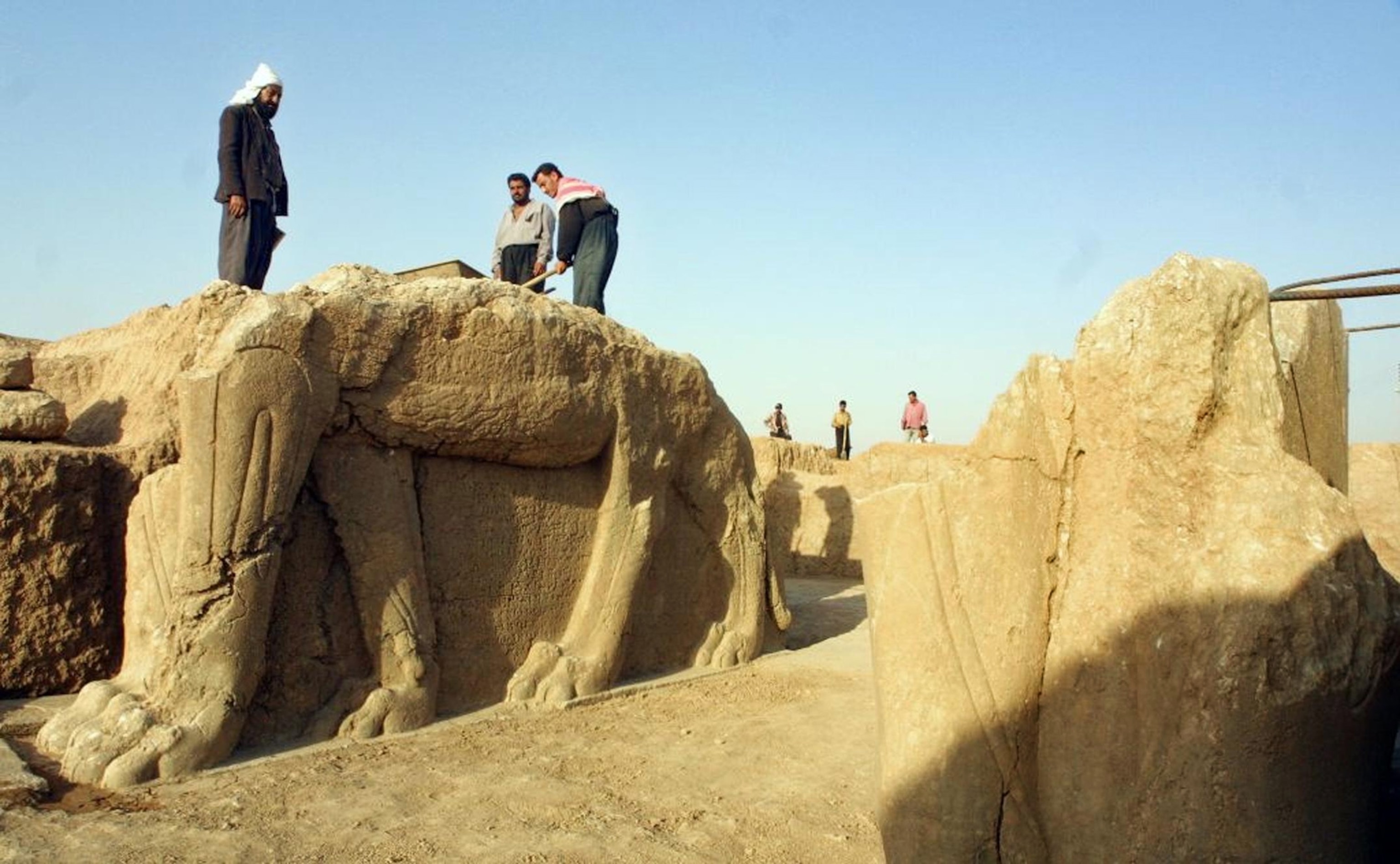 Iraqi workers clean a statue of winged bull at an archeological site in Nimrod