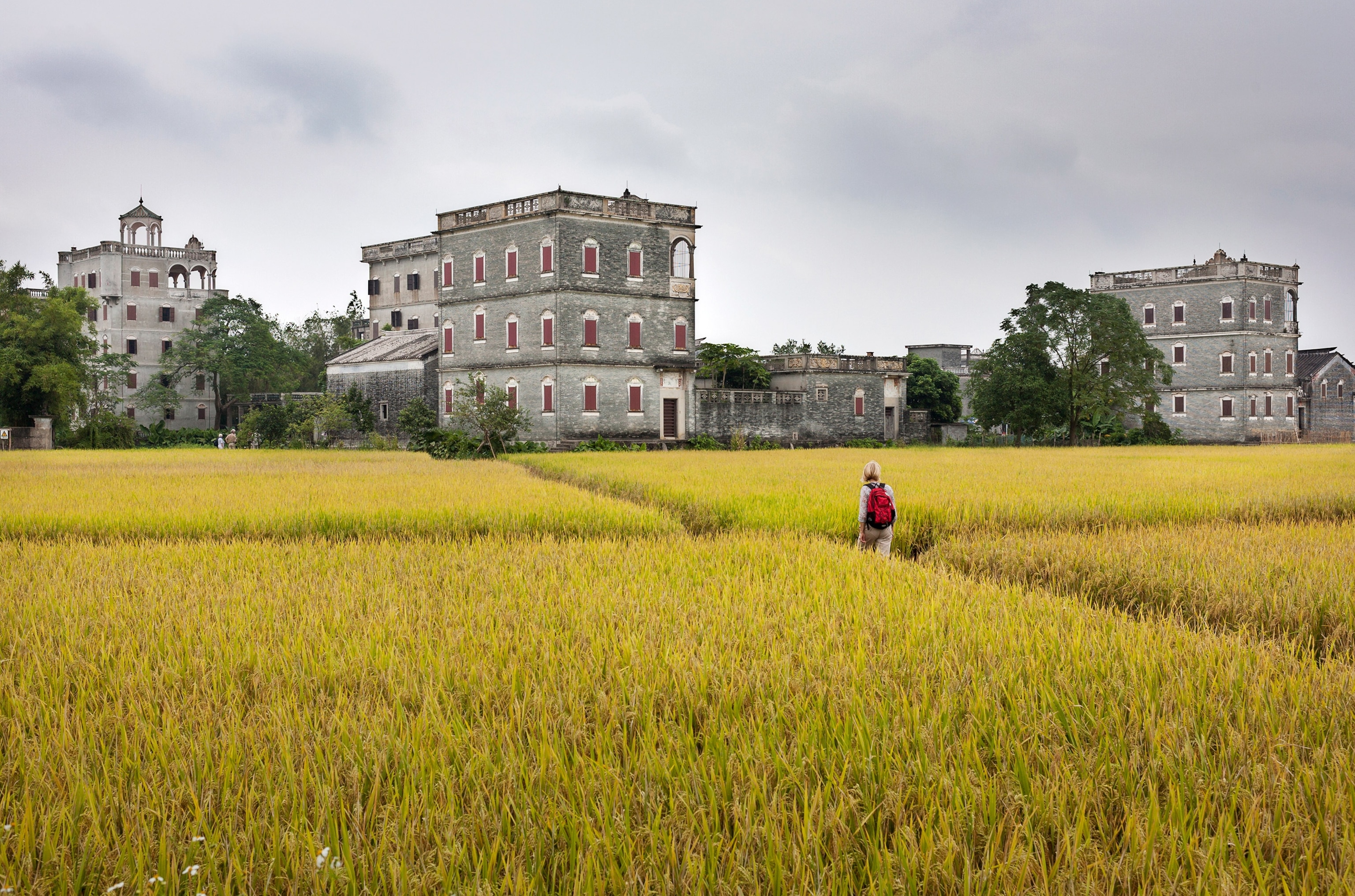 a tourist walking toward the Diaolou towers of Kaiping