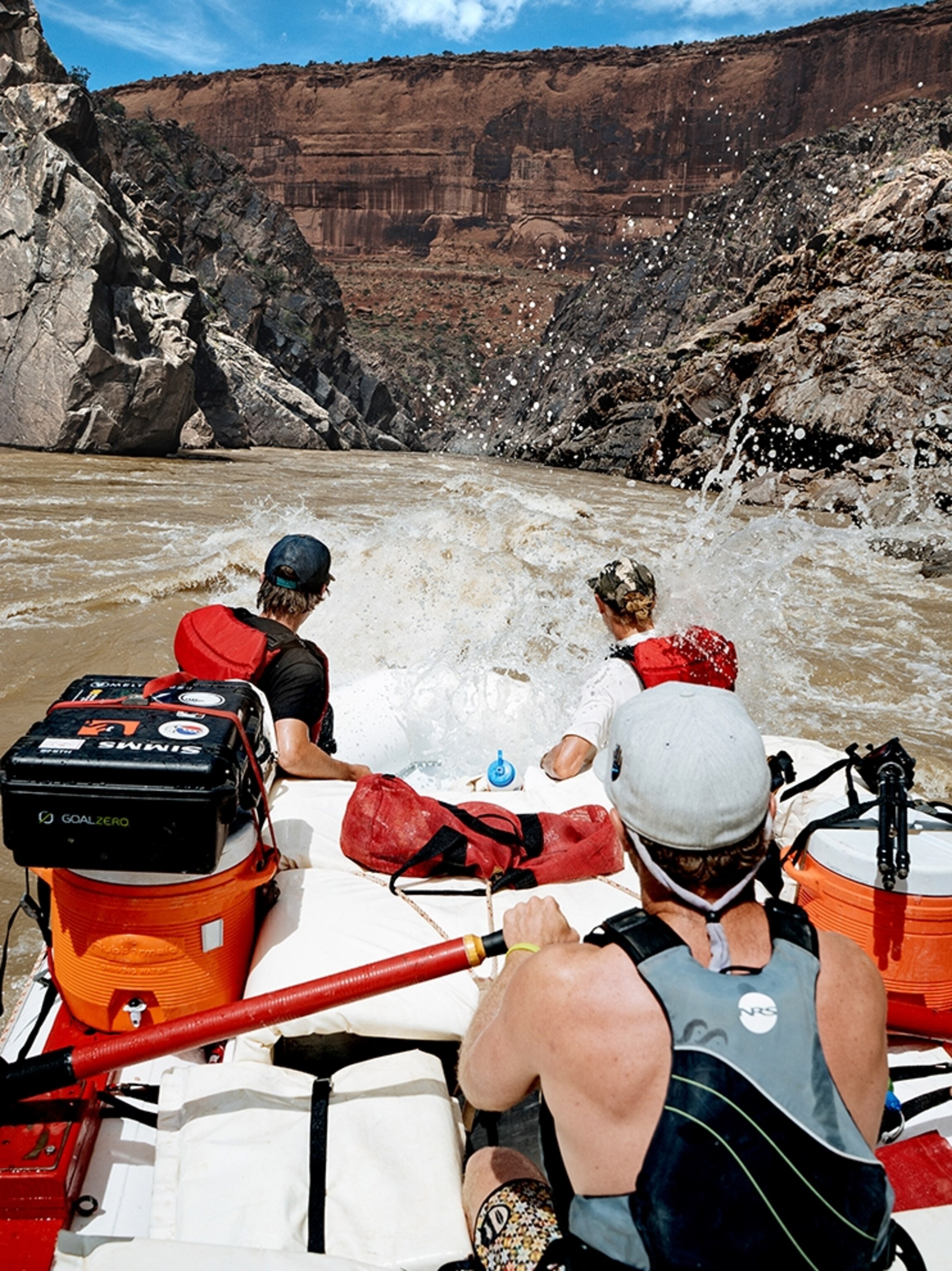 a group of adventurers in riding a white water raft down rapids in Utah.
