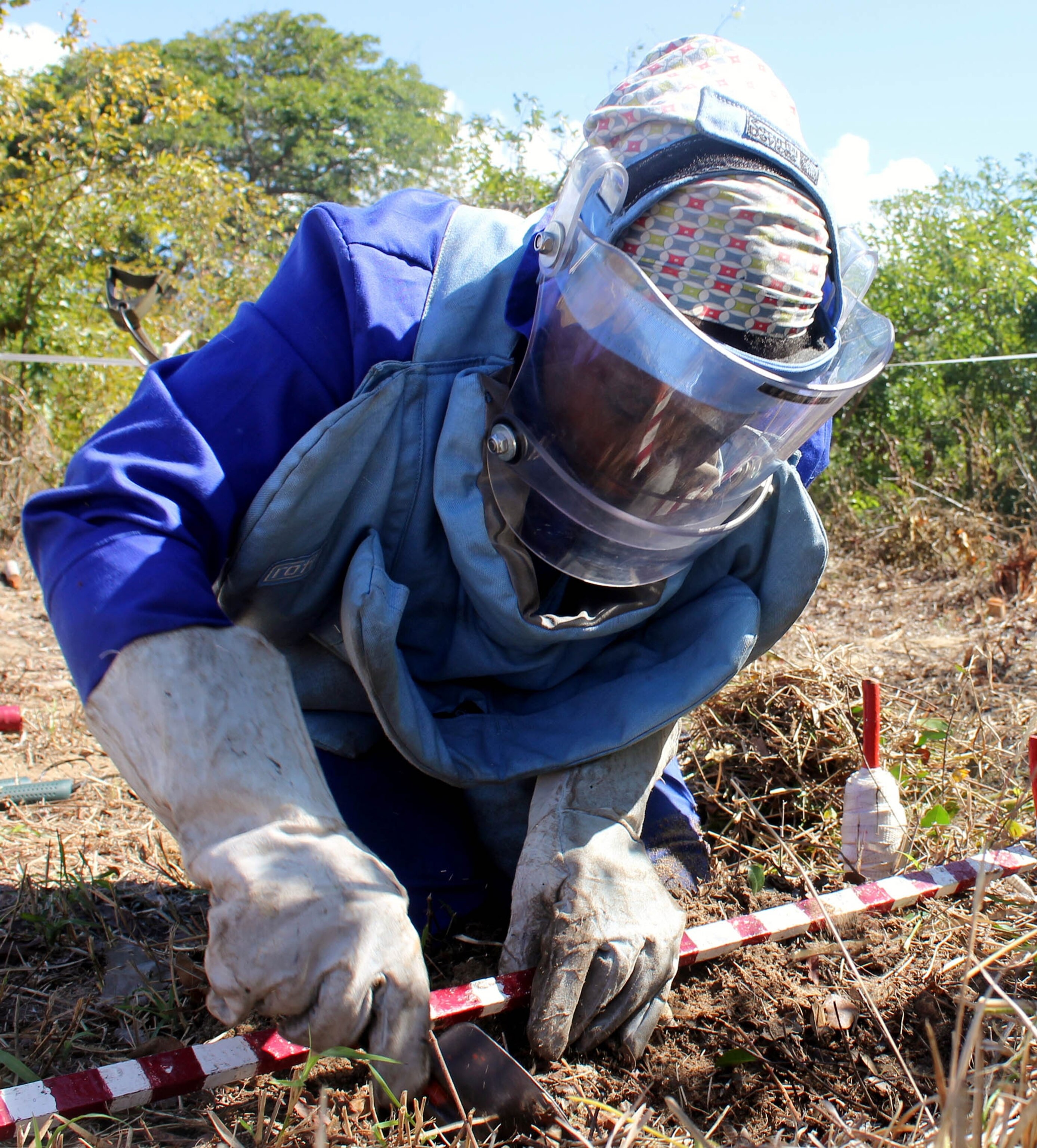 Flora Armando Chipossa Tenho uses a metal detector to search for land mines in southern Mozambique. Government forces placed mines around major infrastructure like these power lines to protect them from sabotage during the country’s long civil war.