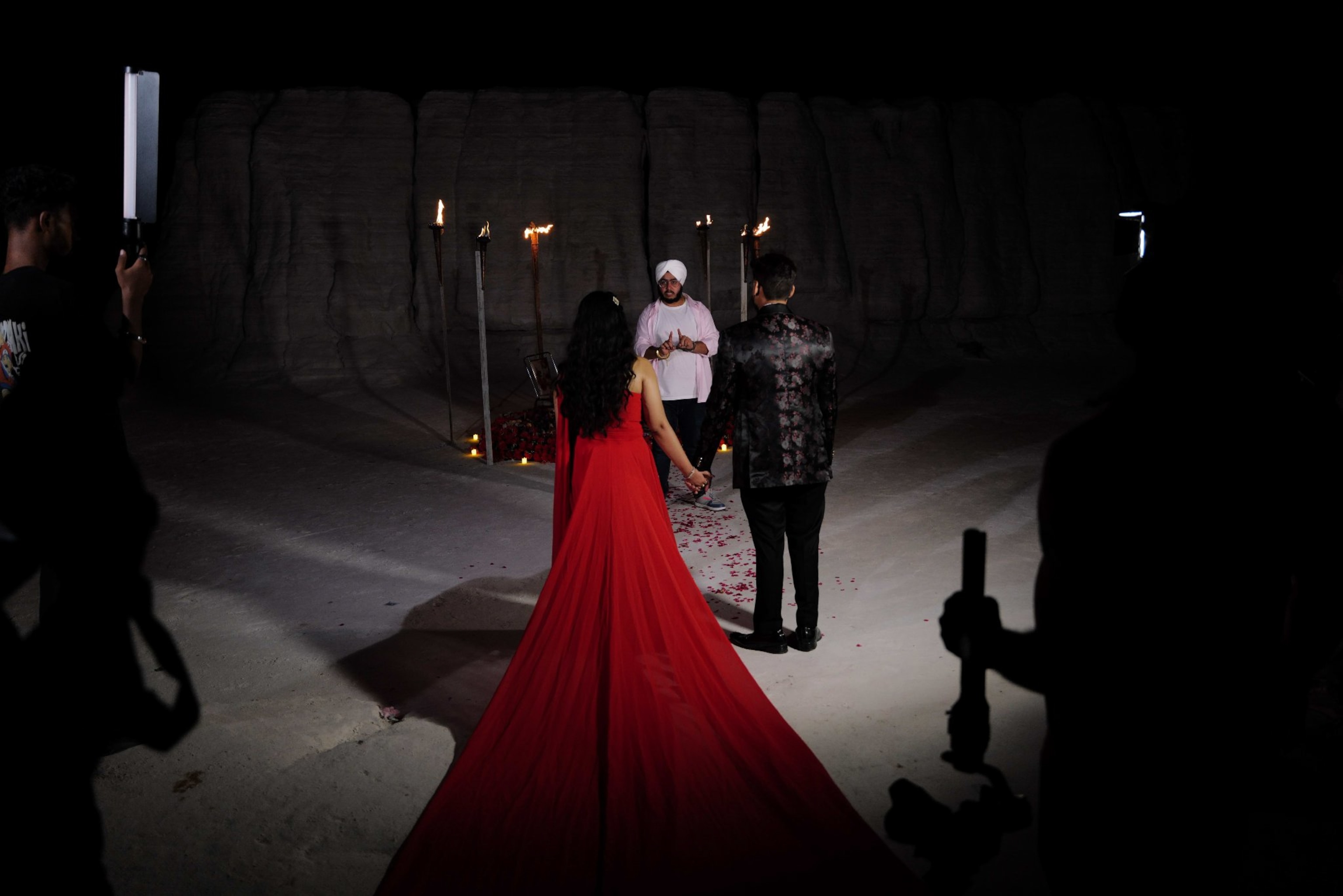 A woman in a red Dress trailing behind her a man holds her hand.