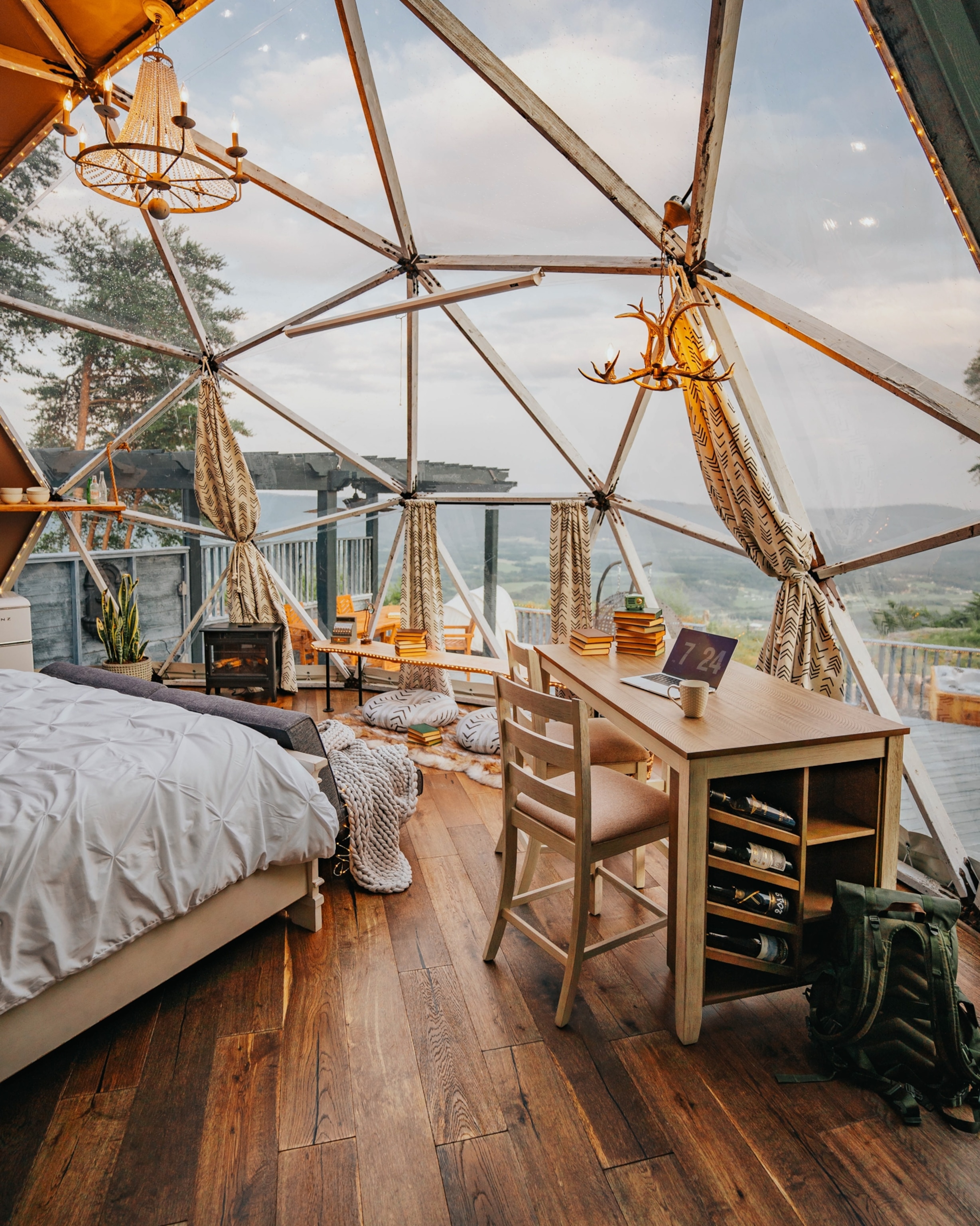 The interior of a geodesic dome cabin at Bolt Farm Treehouse, which is a half-dome of triangular windows full of modern hotel amenities.