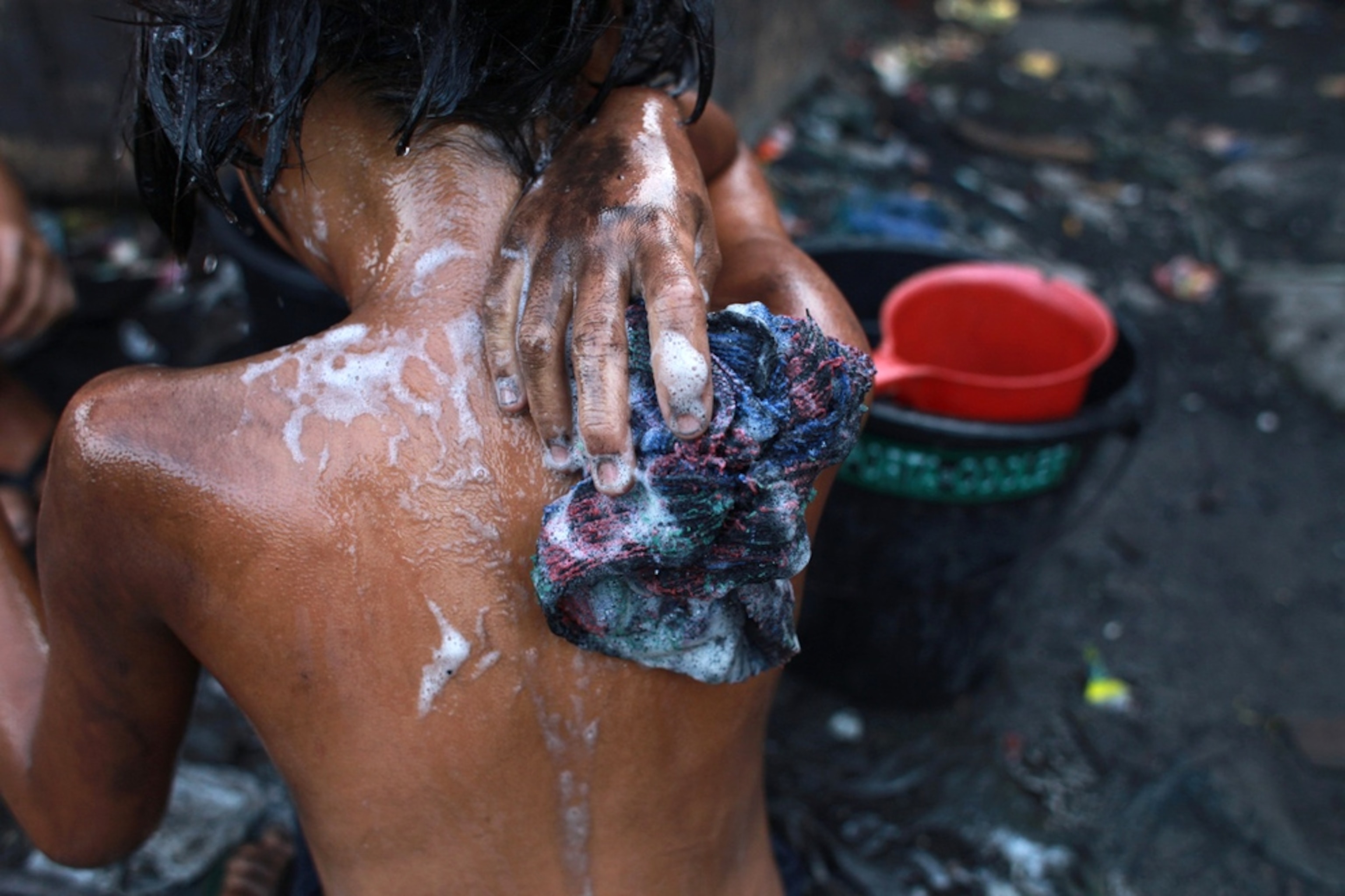 A girl washes the soot and charcoal off her body, Manila