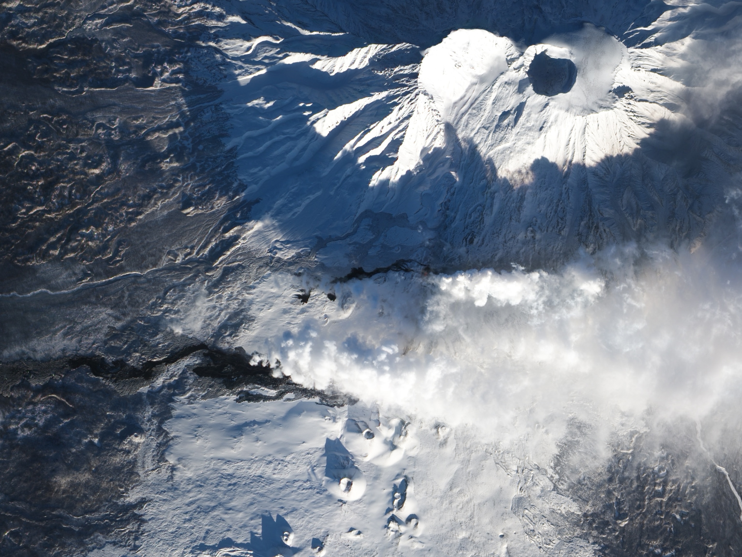 Tolbachik picture - the volcano spews steam and lava from active fissures on its flank