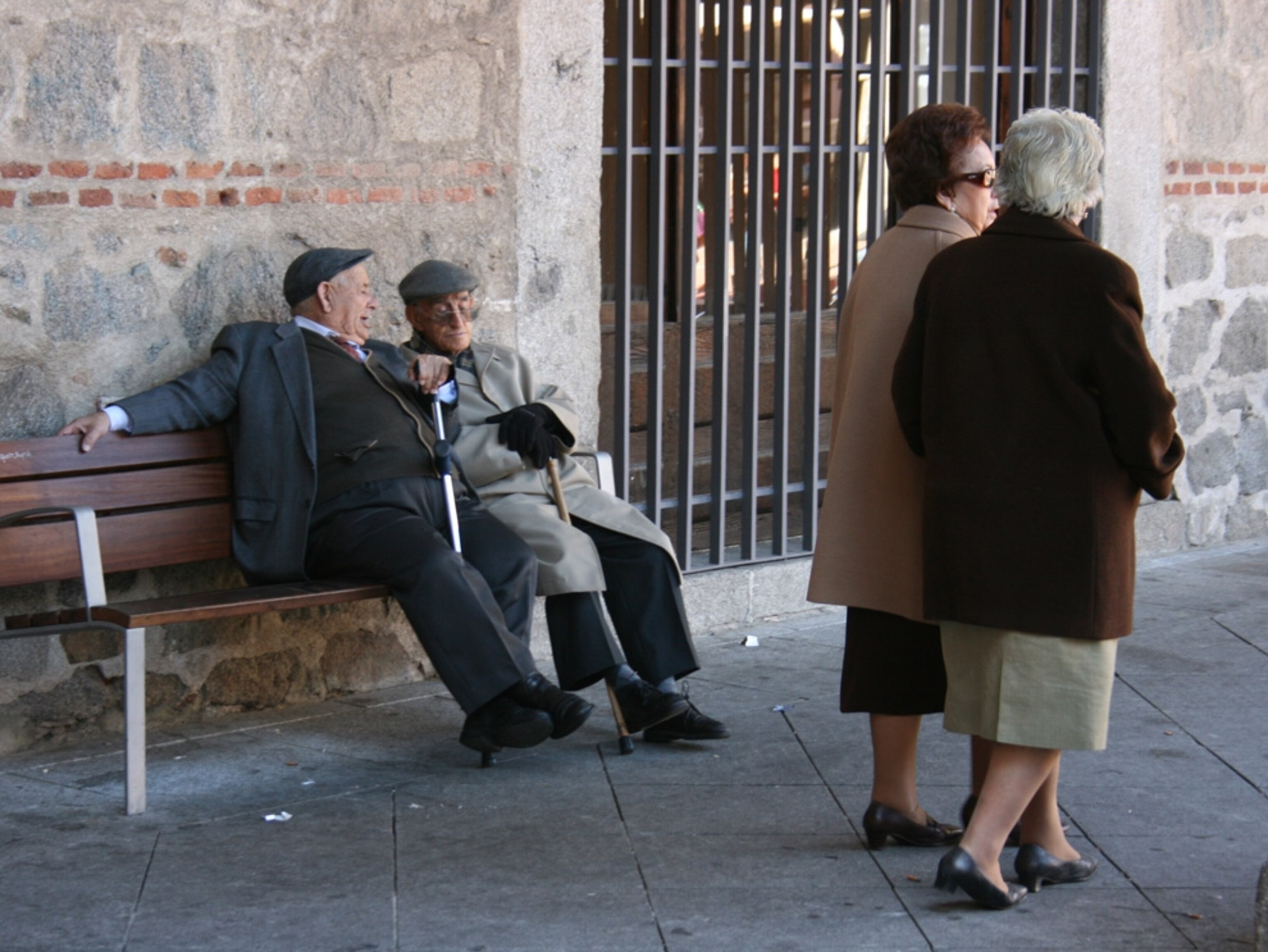 This picture was taken in the Main Plaza of Avila, Spain, in the Autum of 2008. Two elderly men are having a conversation while two women of similar age walk by in a beautiful October afternoon. Avila is a medieval town in the heart of Spain that has kept is ancient charm in its arquitecture, and where its inhabitants are proud of their traditions.