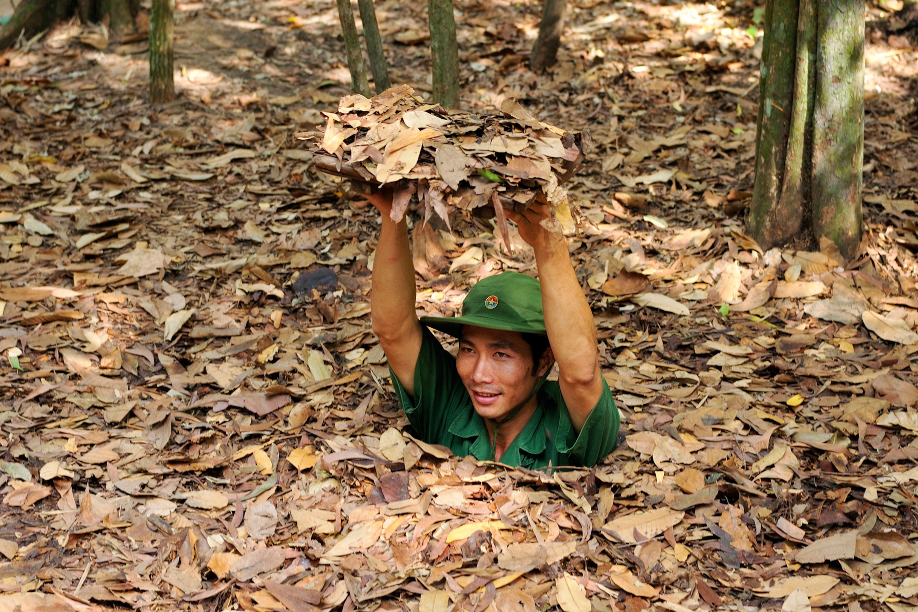 A man pops out of a tunnel entrance wearing a helmet.