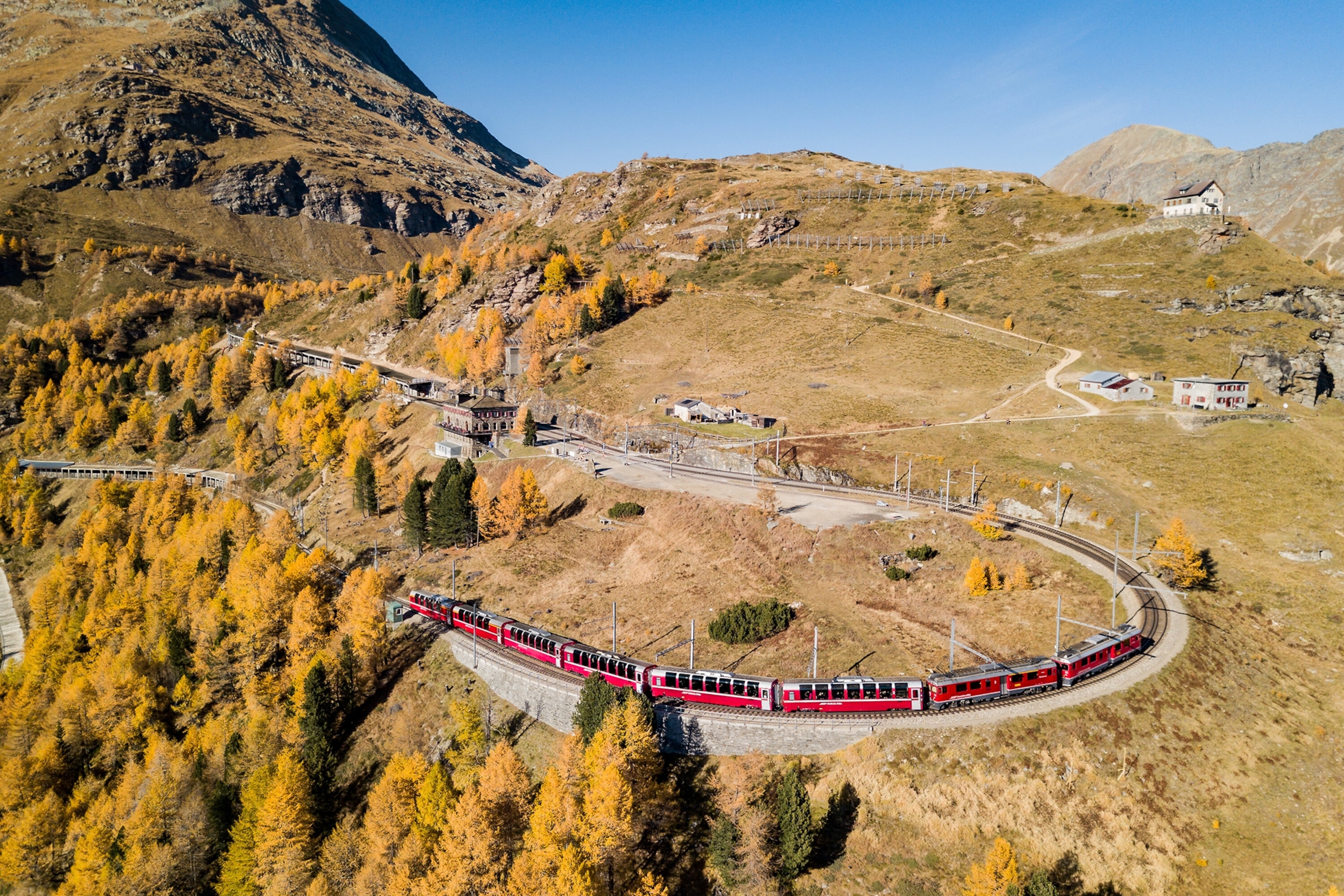 A train passes through a sunny, mountainous landscape