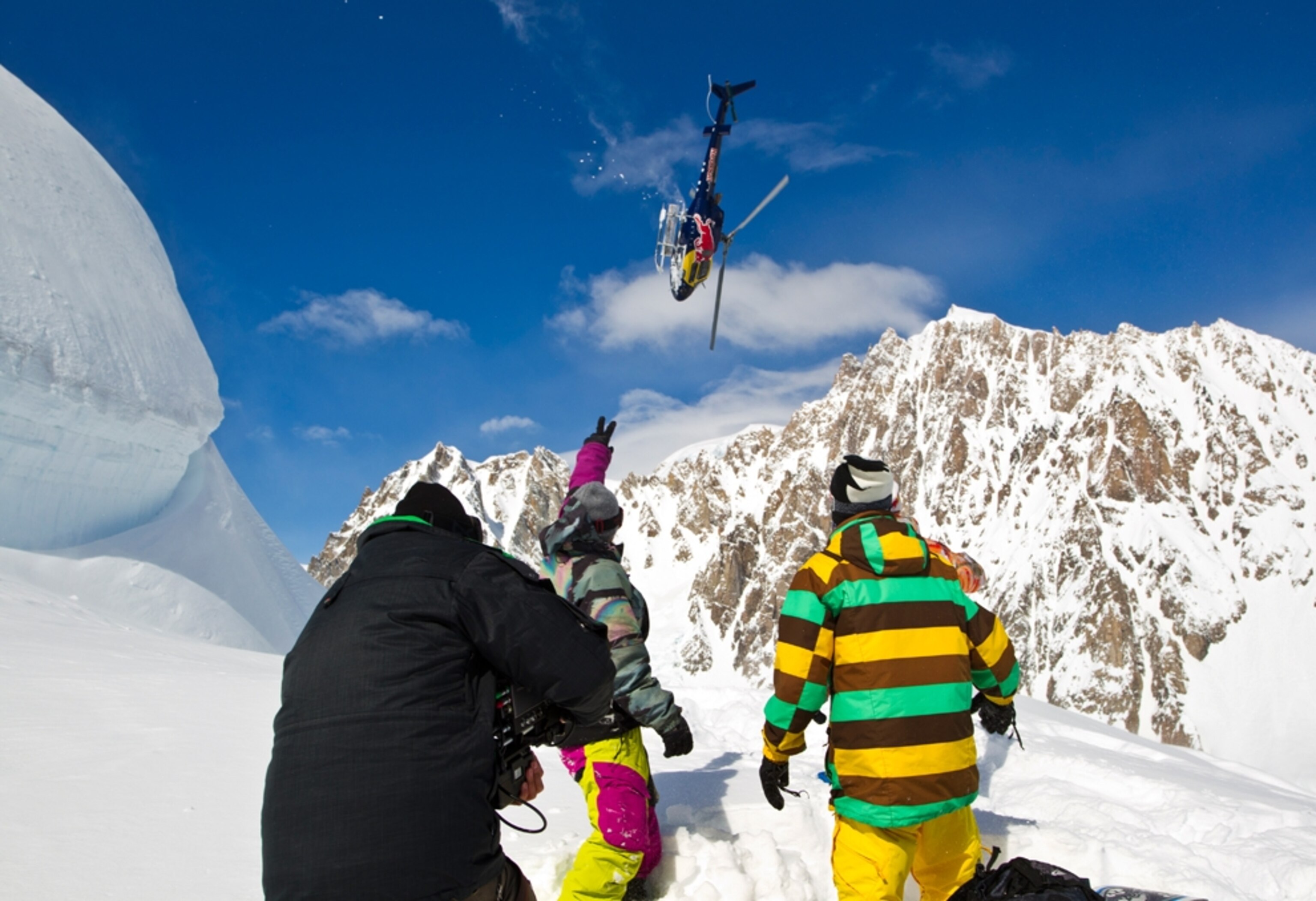 Snowboarders watch a helicopter film in Alaska