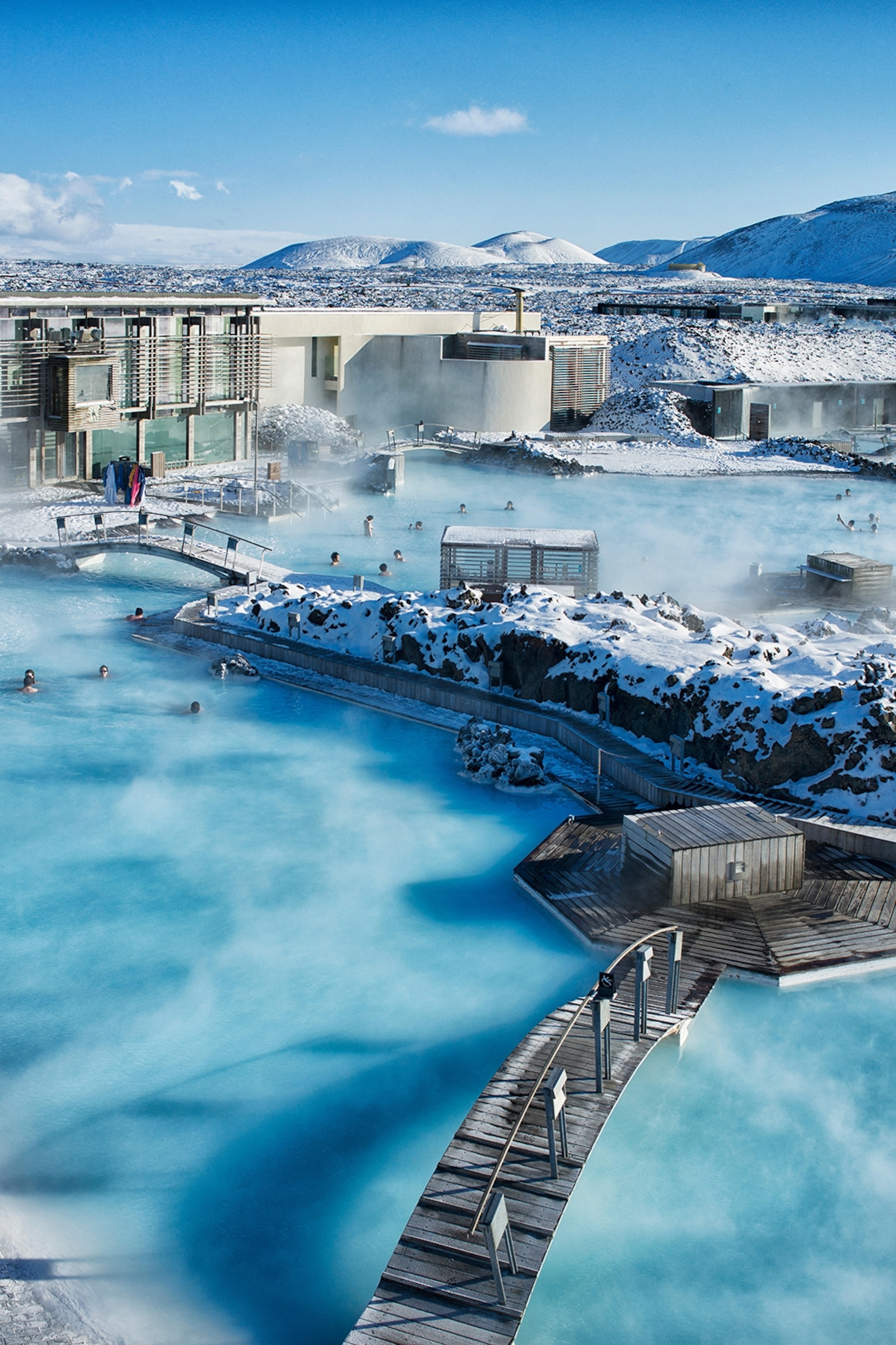 A birds-eye shot of a steaming lagoon in an icy and rocky landscape.