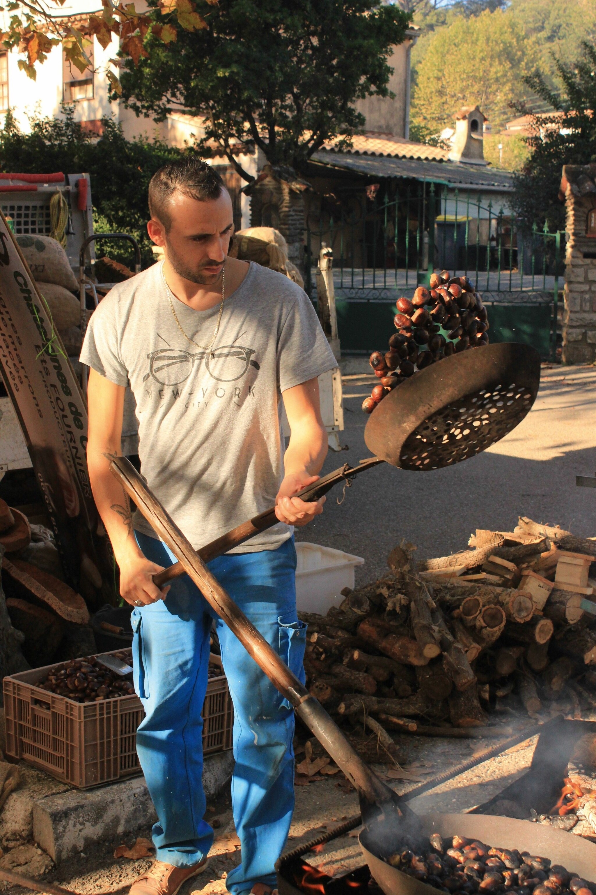 A man flipping roasting chestnuts in a pan.