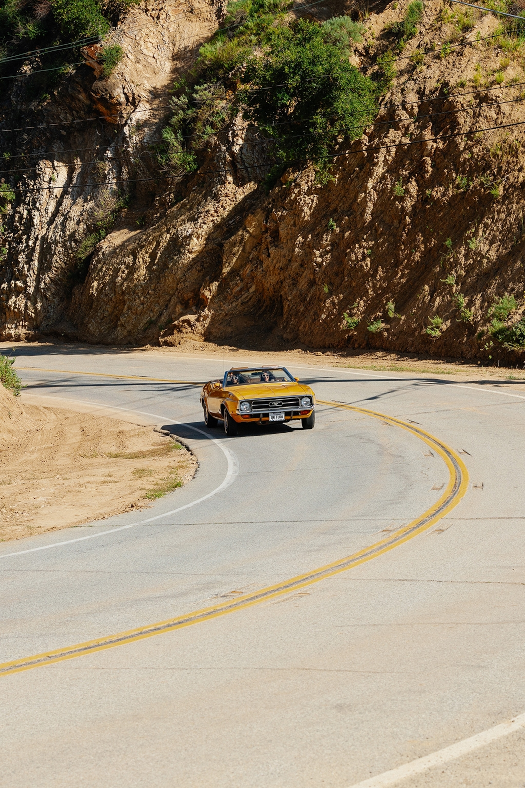 A retro racing car swiftly taking a corner on a winding mountain road.