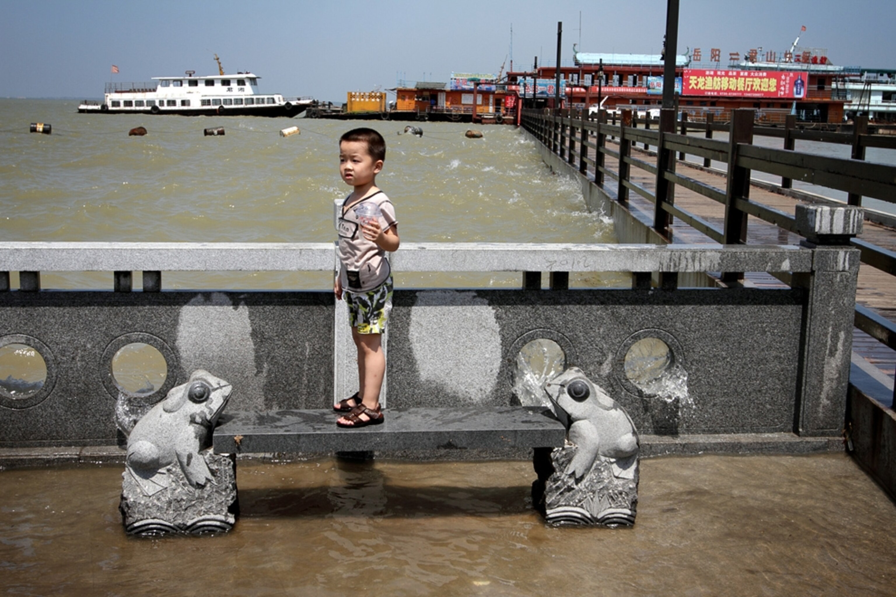A young boy stands near flooded Dongting Lake, in central Hunan Province