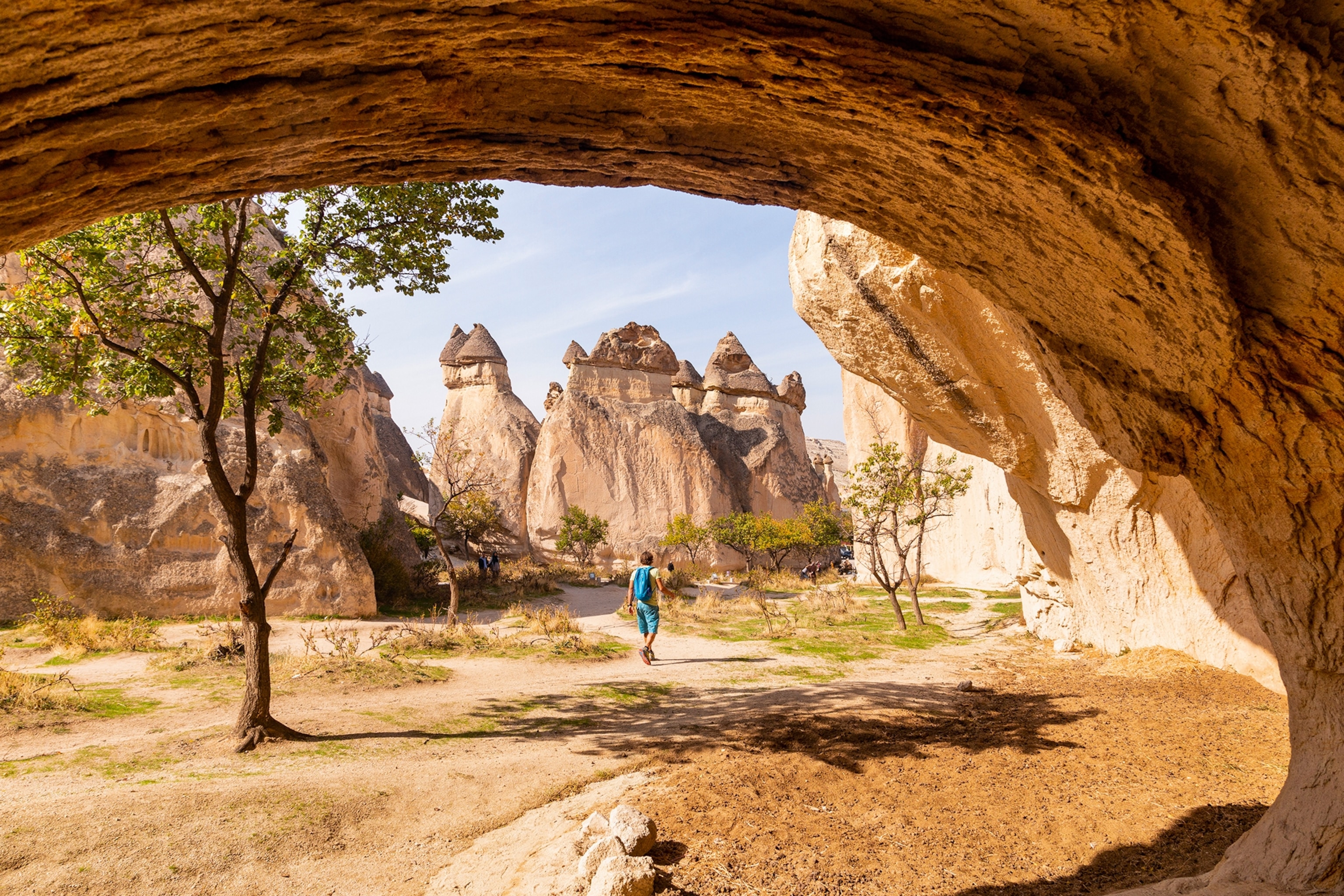 Cave opening showing a hiker walking towards rock formations