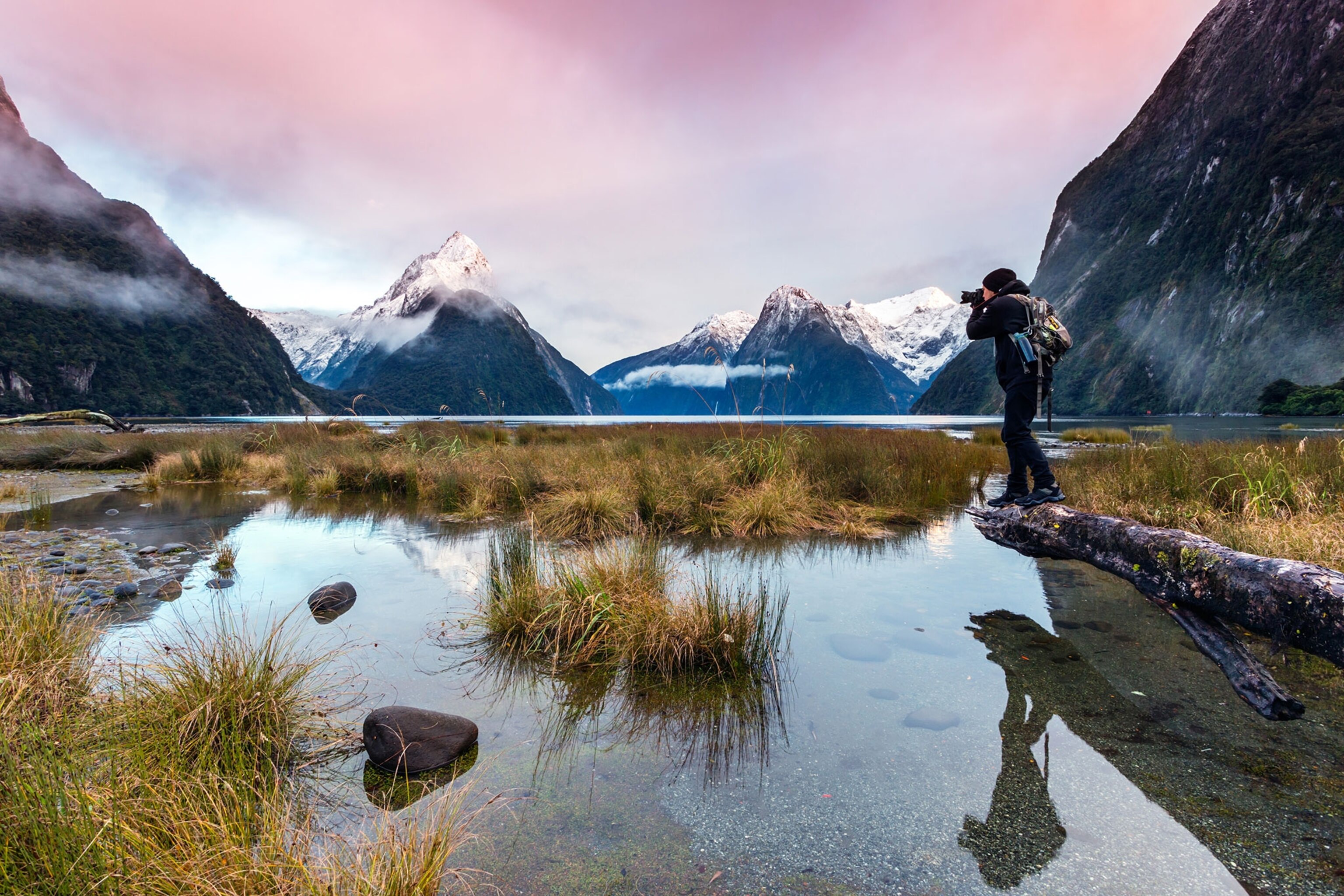 a man photographing sunset at Milford Sound, Fiordland National Park, New Zealand