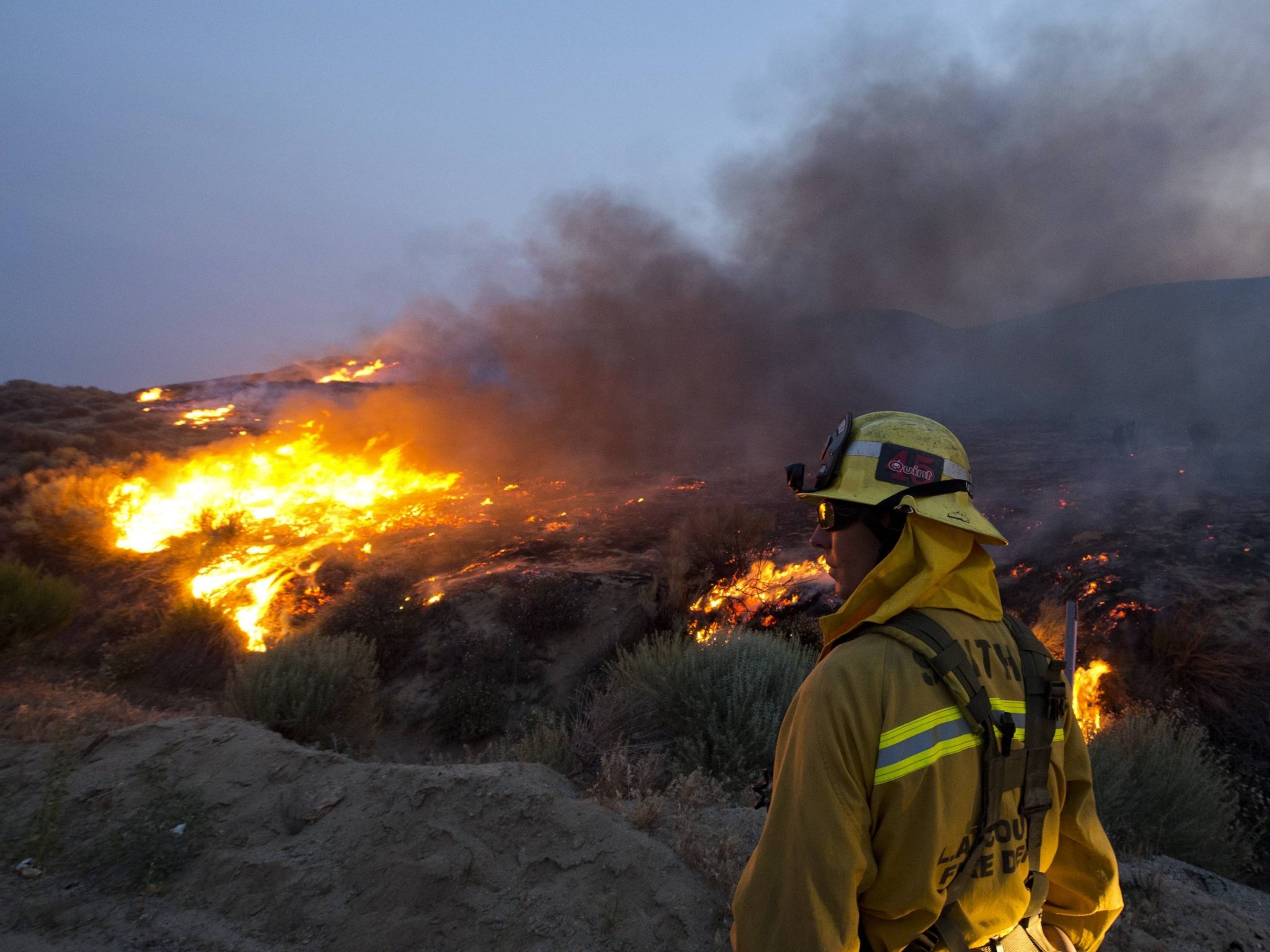 a firefighter watching burning brush