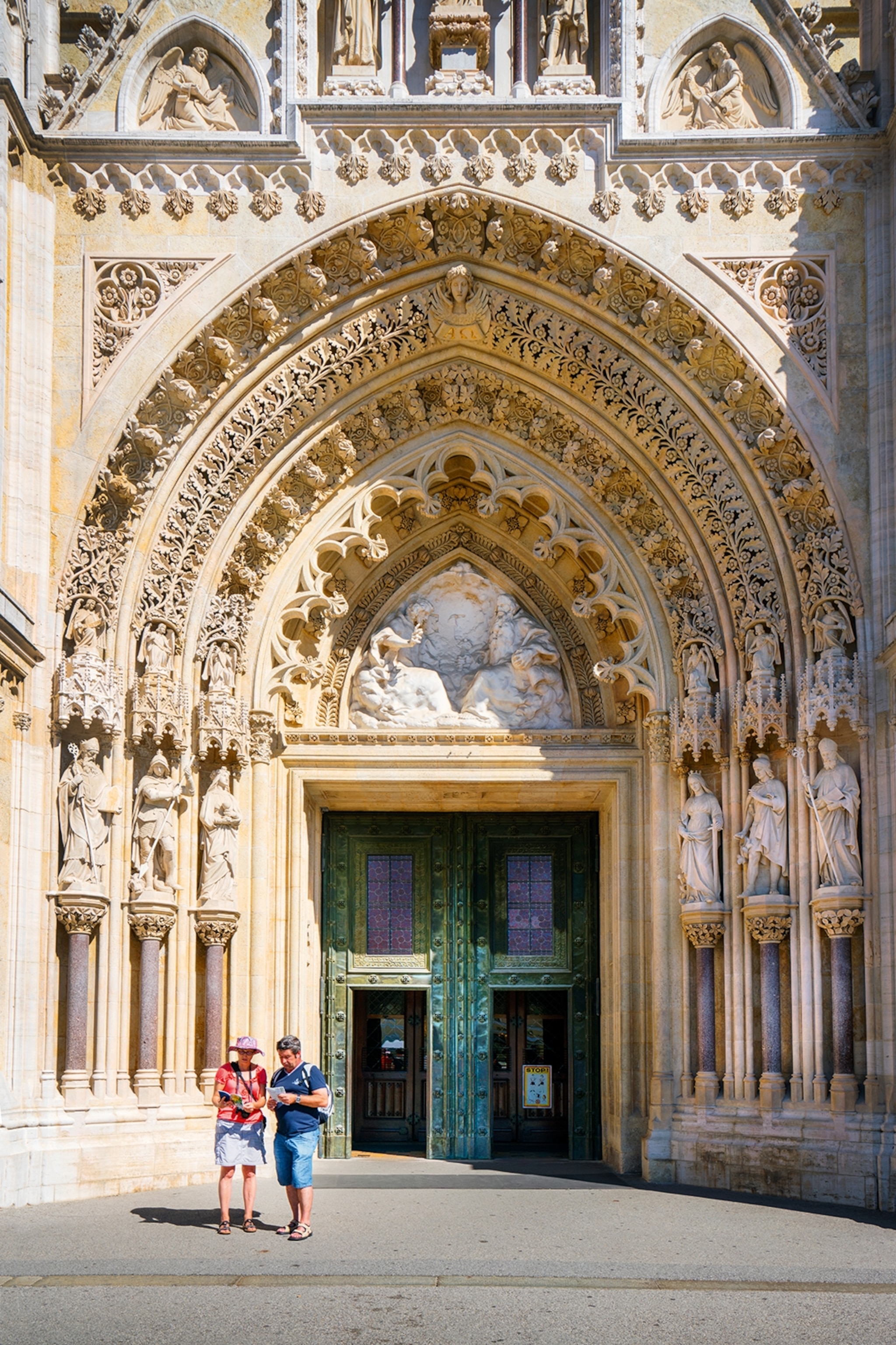 The gates of a cathedral with multiple rings and statues adorning the ceiling.