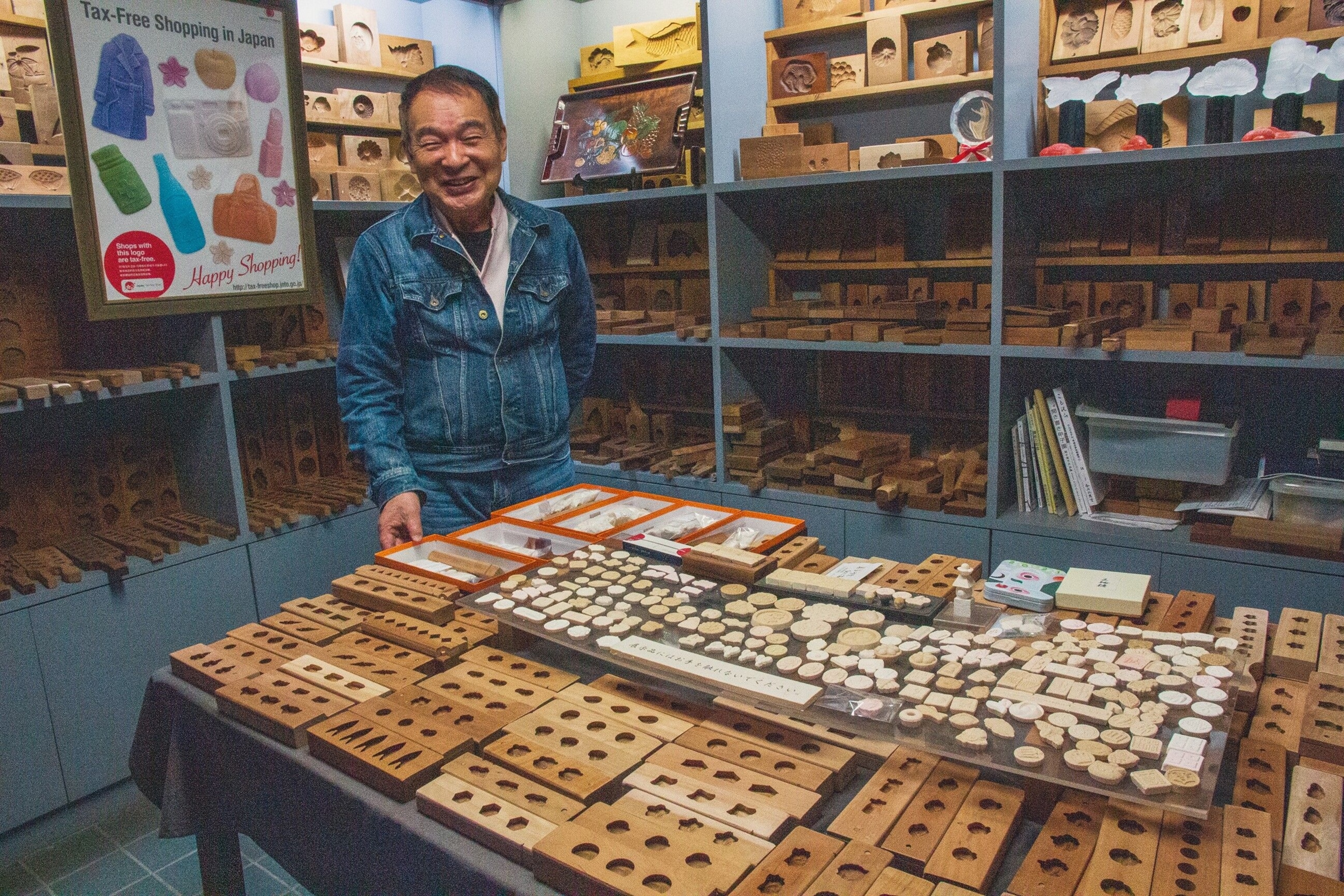 Yoshihiro Ichihara, stood in a room full of various collectors' items and building materials.