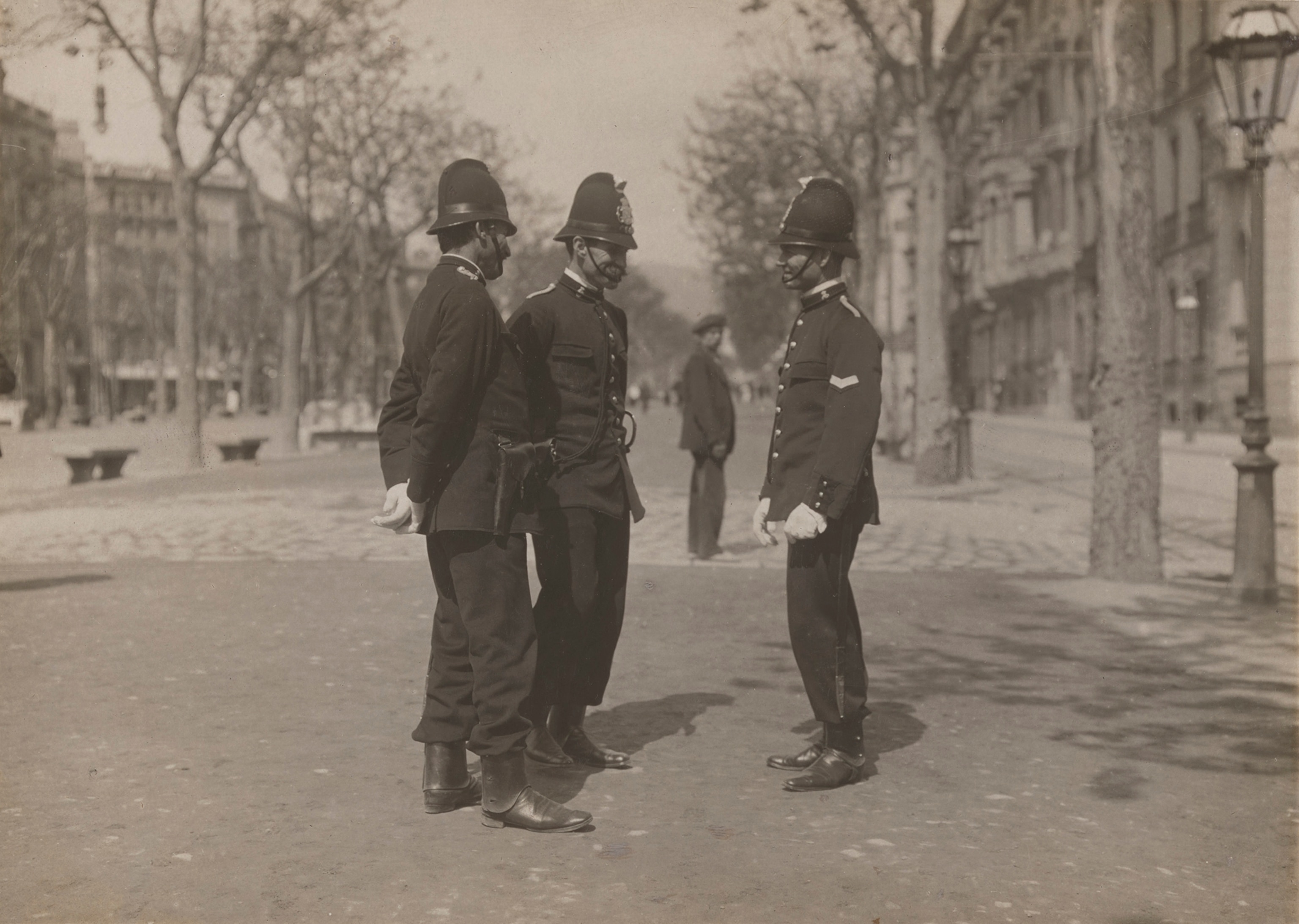 Three police officers stand on a street in Barcelona.