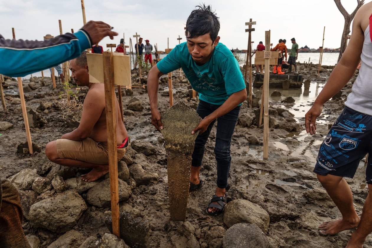 A boy removes a grave marker from a flooded cemetery.