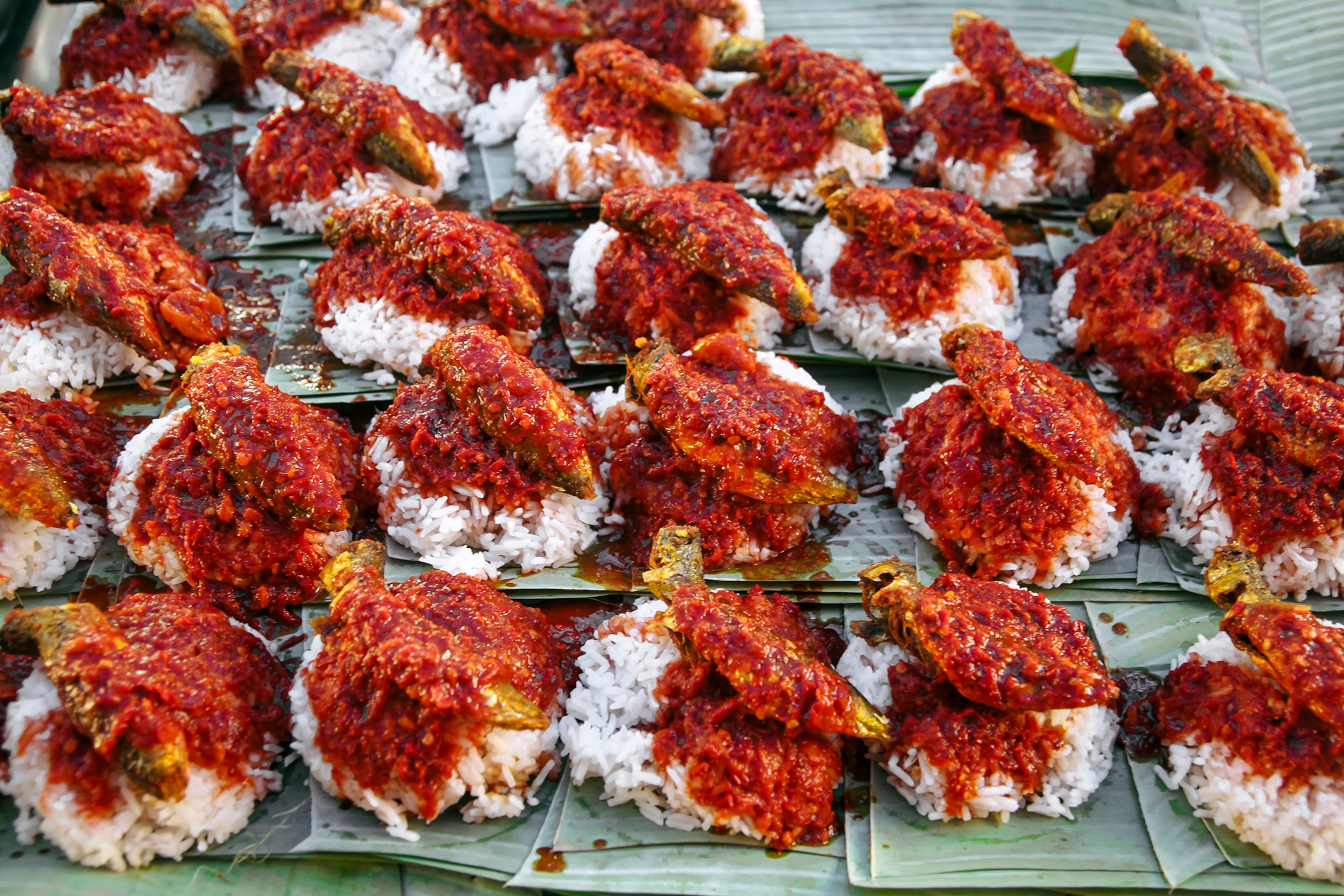 椰浆饭的特写视图,上面撒上参巴辣椒酱和香蕉叶上的 Ikan tambam。
