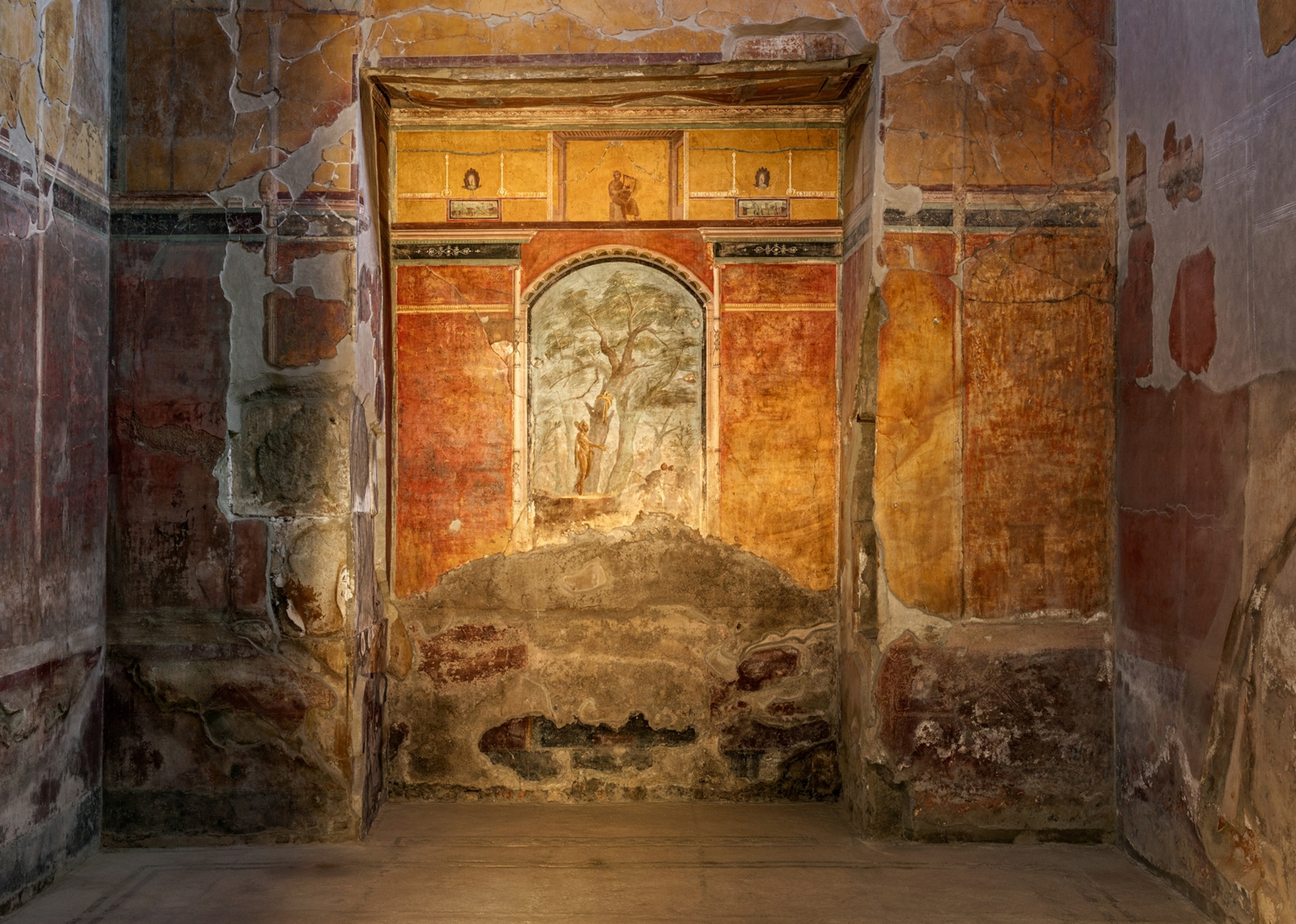 A small section of a building with faded orange and blue frescoes on the wall.