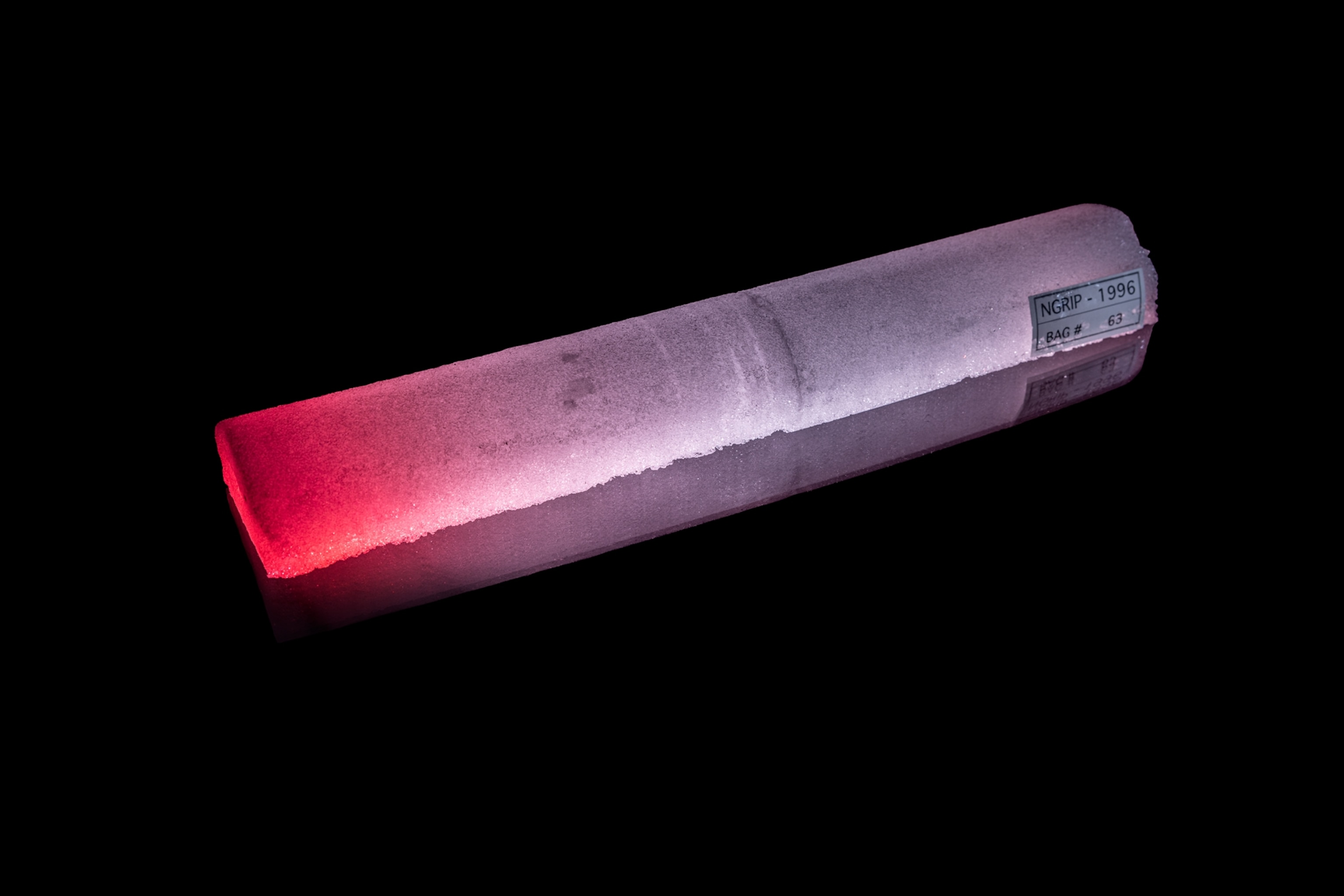 Cylindrical block of ice gloving red on one end and flue on another.