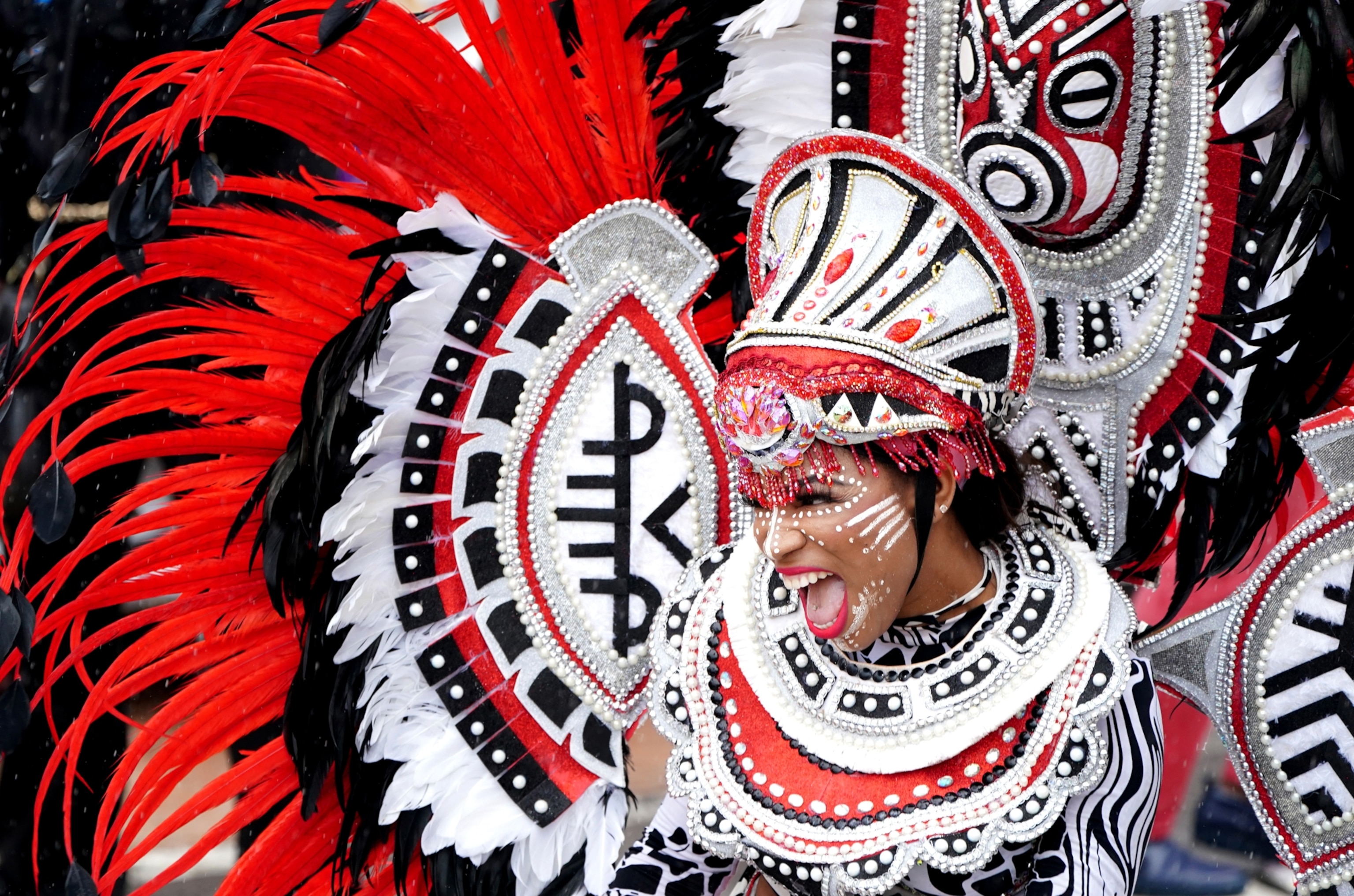 A woman, with red and white feathers on her body smiles brightly.