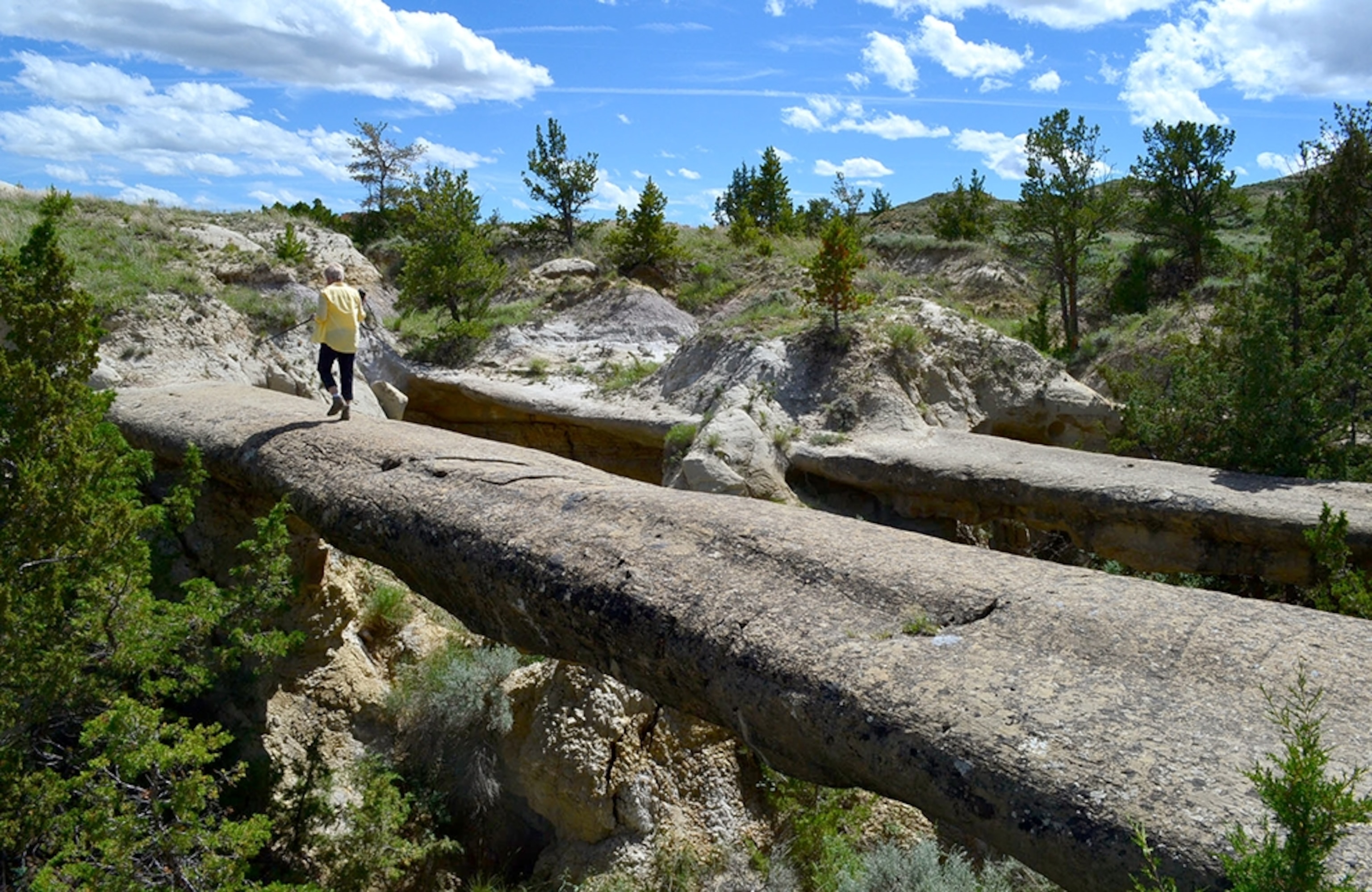 a person walking across the natural sandstone bridges on the Calypso Trail
