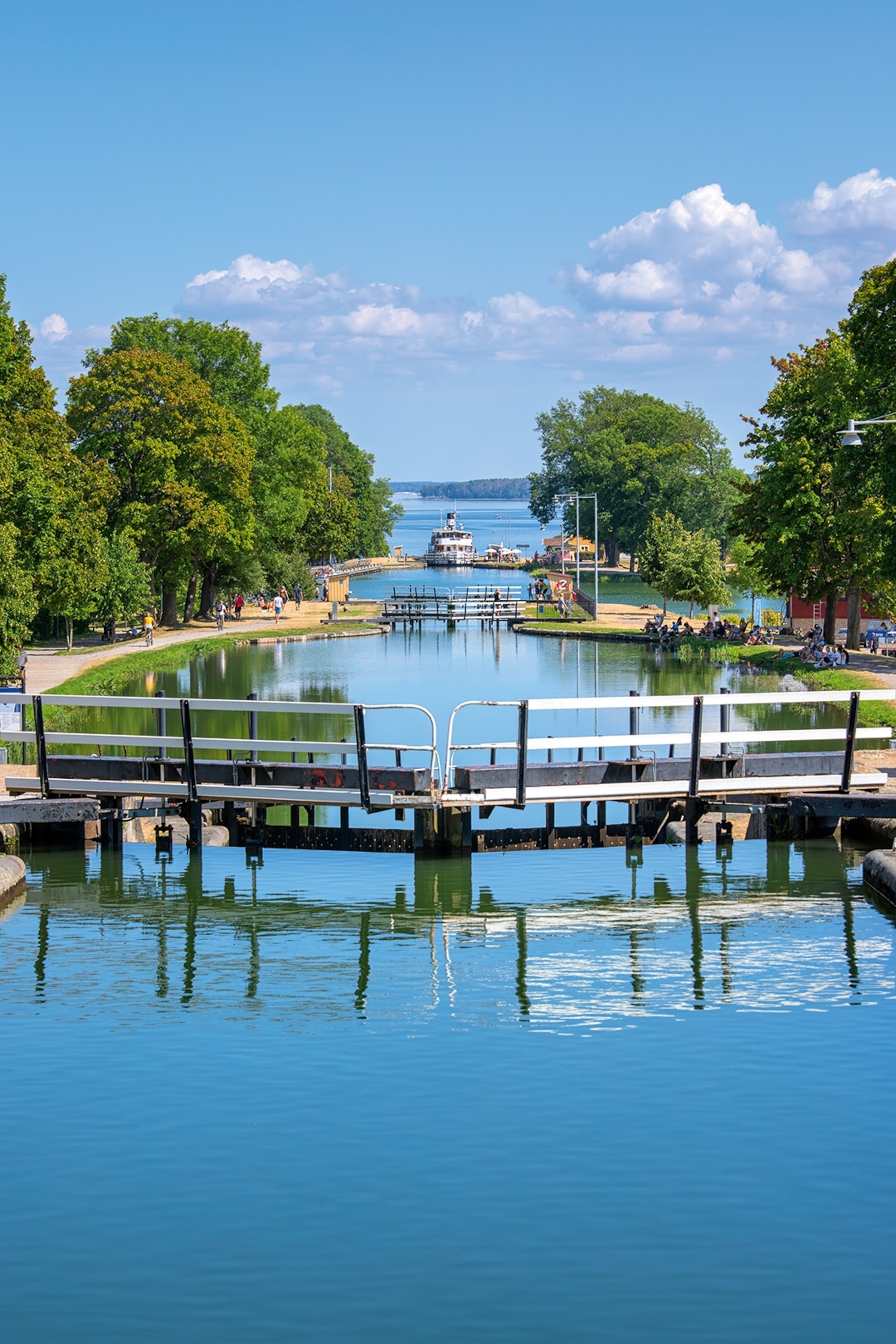 A boat heading for a river lock with greenery on either side.