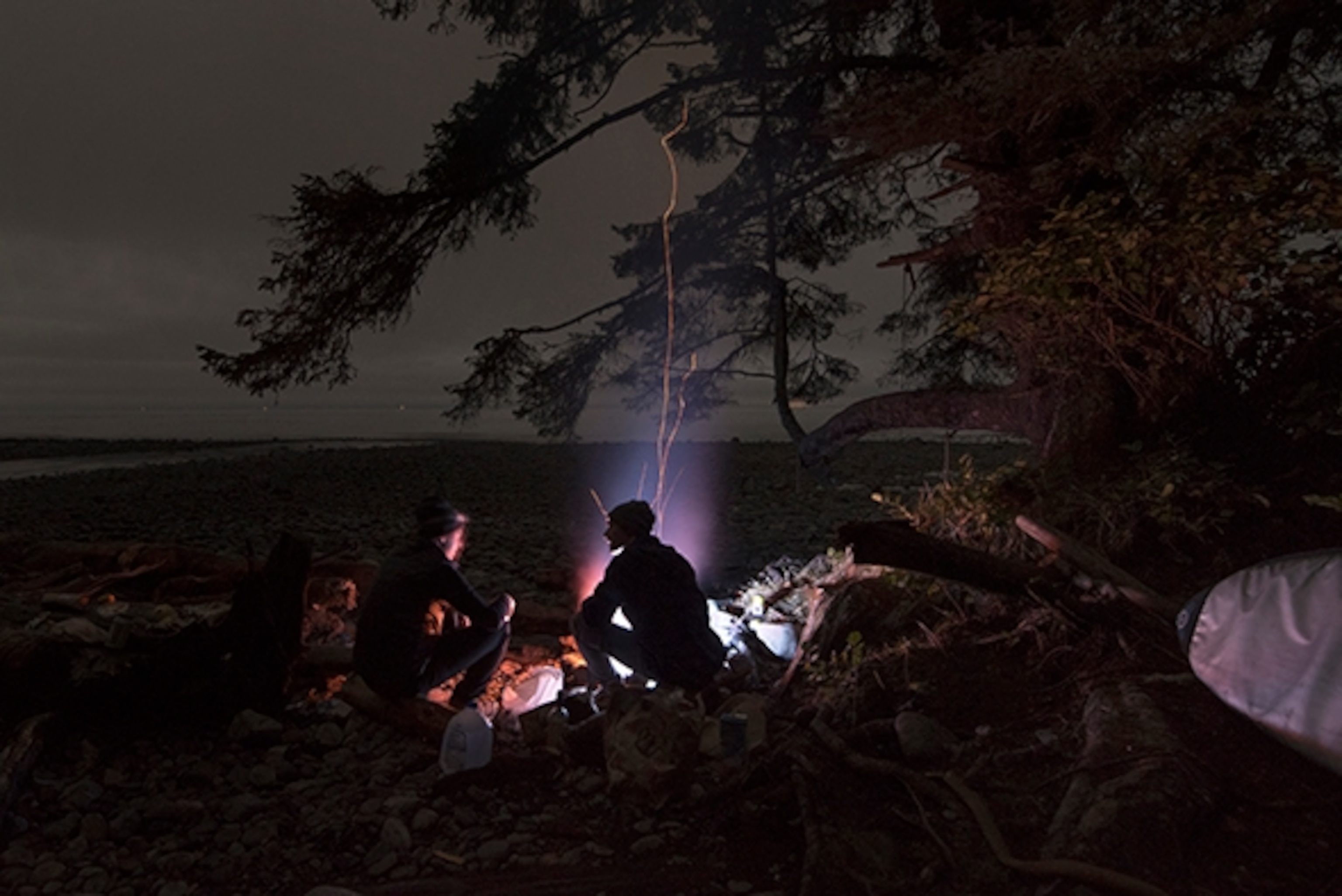 Eliel Hindert and Alex Guiry sit around our camp fire cooking dinner at Sombrio, Vancouver Island, British Columbia; Photograph by Max Lowe