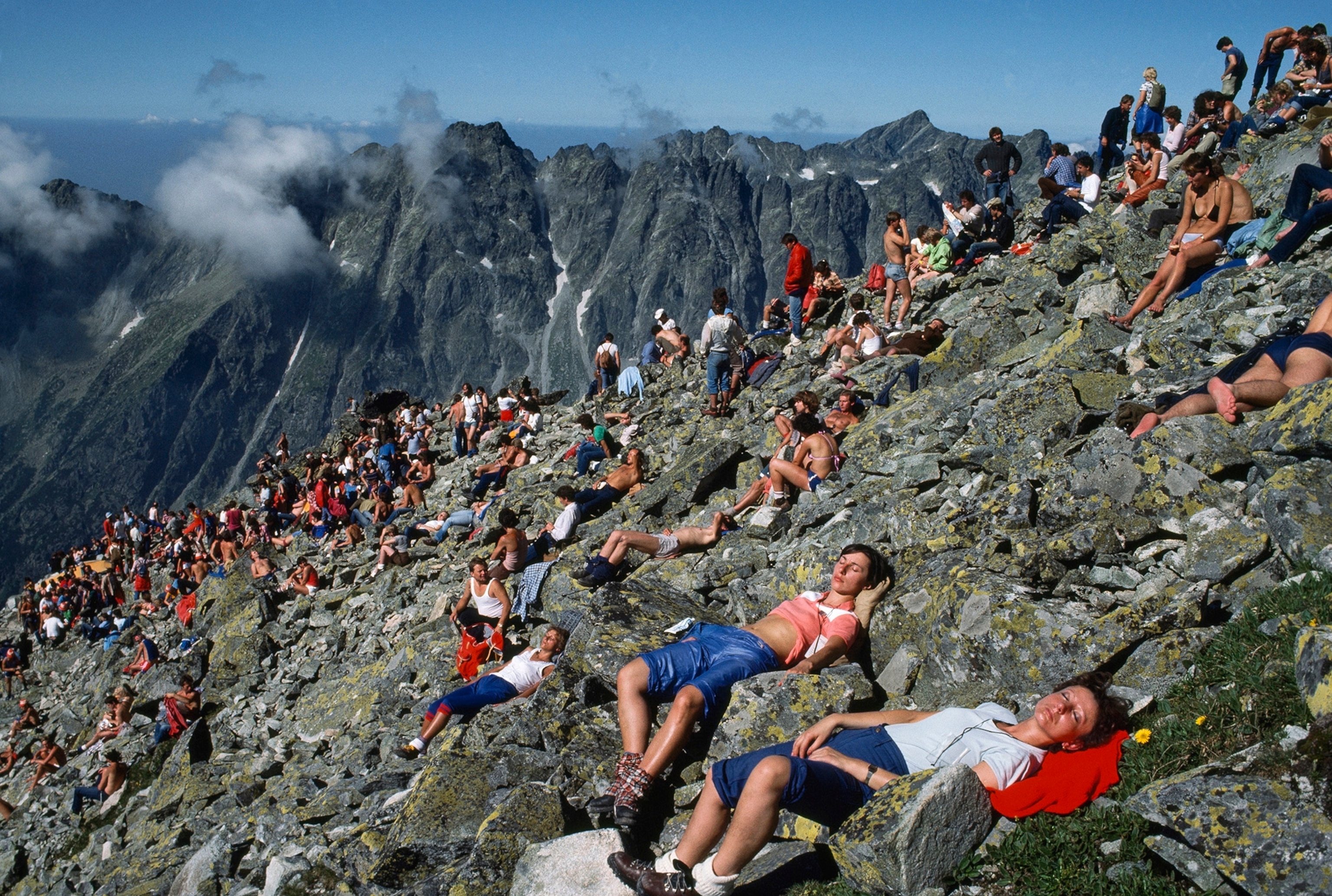 A mass of people lay on a bed of rocks high up in the mountains.