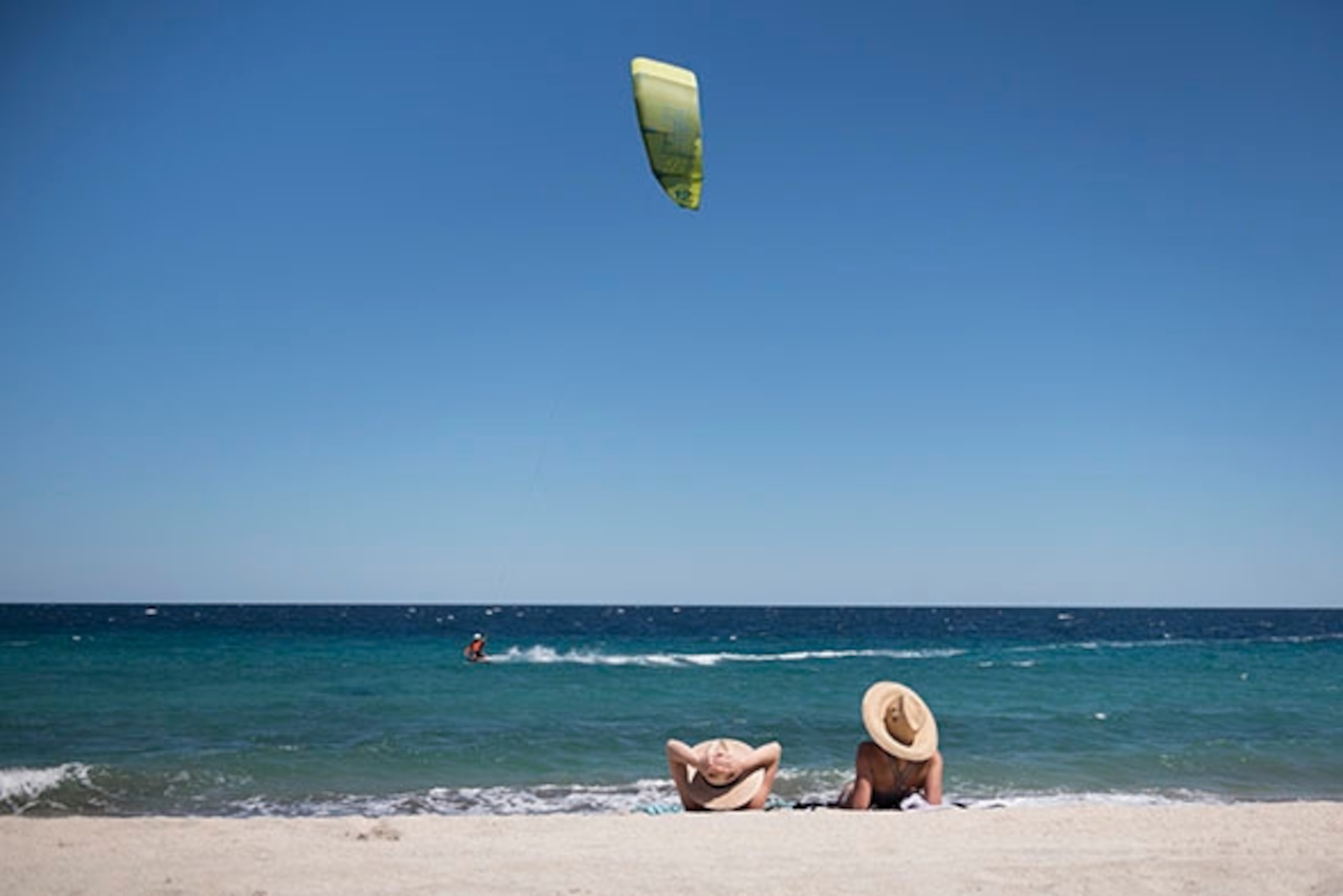Mary Macintyre and Catherine sit watching kite borders sail on the beach near Los Barilles; Photograph by Max Lowe
